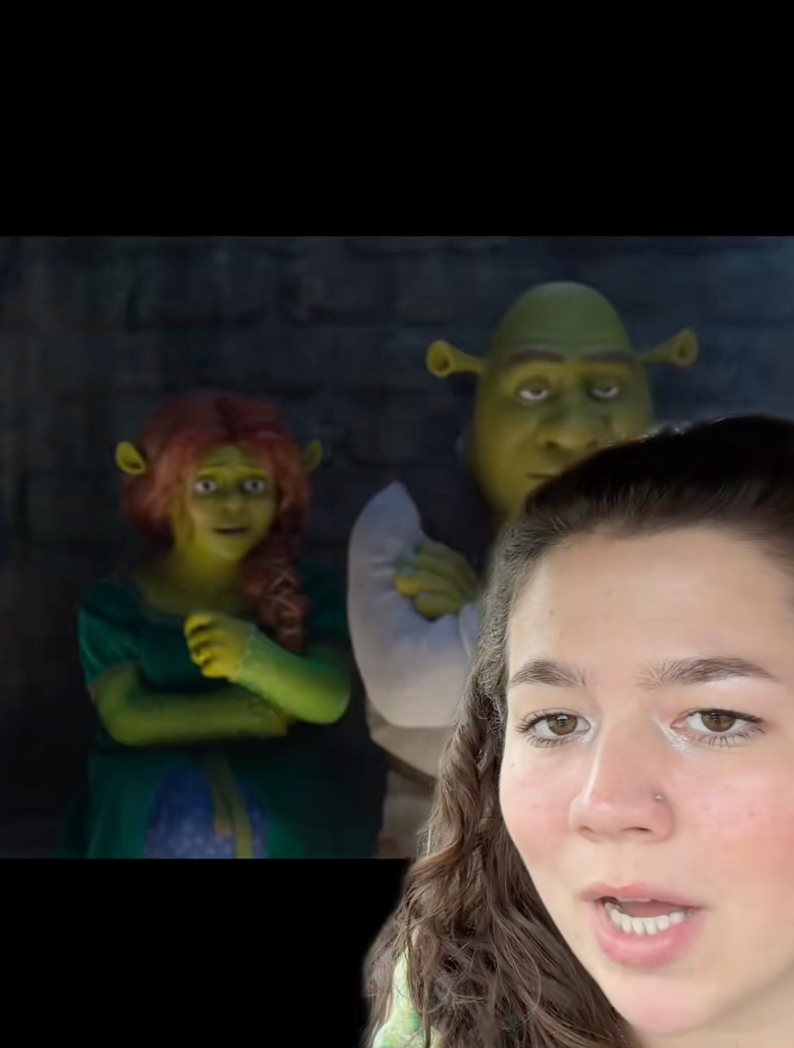 Animated ogres standing together in a dim setting; a person in the foreground appears to comment on the scene
