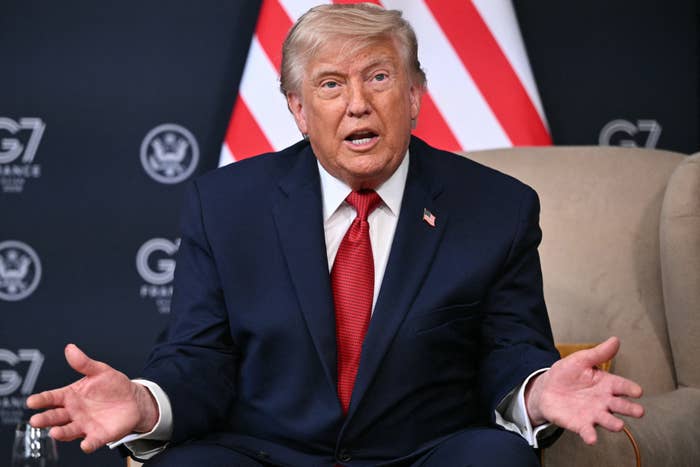 A idiosyncratic   successful  a suit   gestures with hands unfastened  during a ceremonial  lawsuit   with G7 logos successful  the background