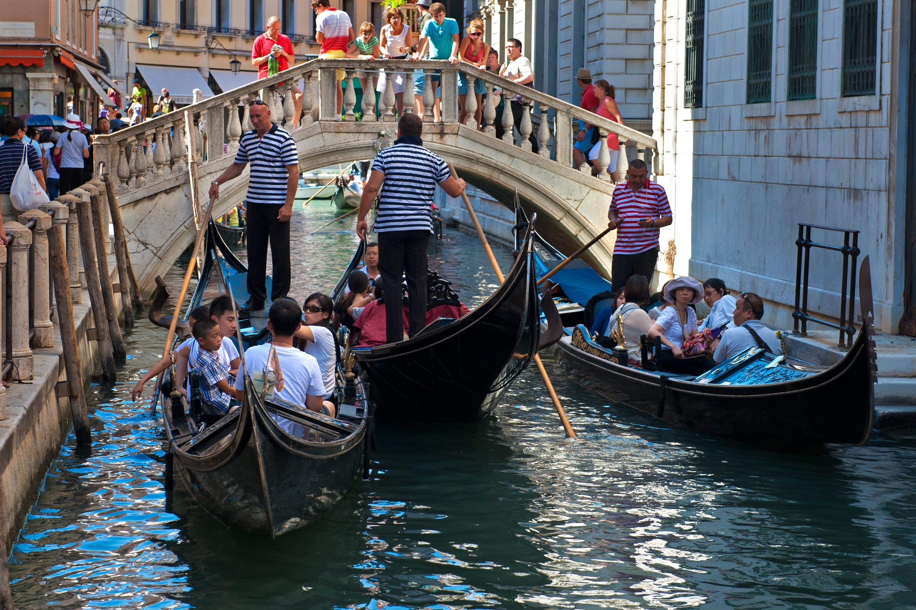 Gondolas navigate a engaged Venice canal nether a chromatic bridge, with gondoliers and tourists enjoying the picturesque scene