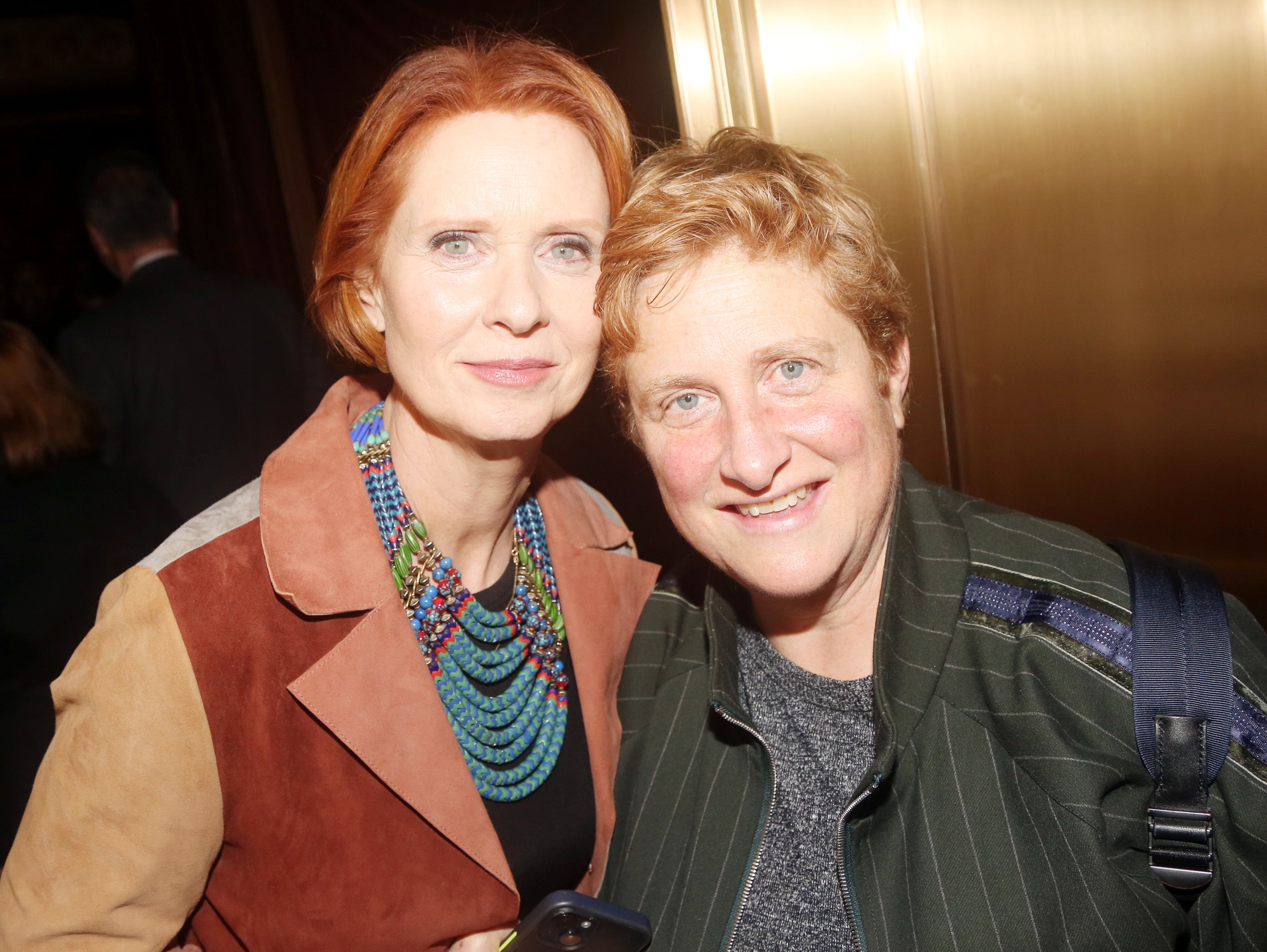 Two radical airs together. One wears a multicolored beaded necklace with a suede jacket, the different wears a pinstripe suit jacket
