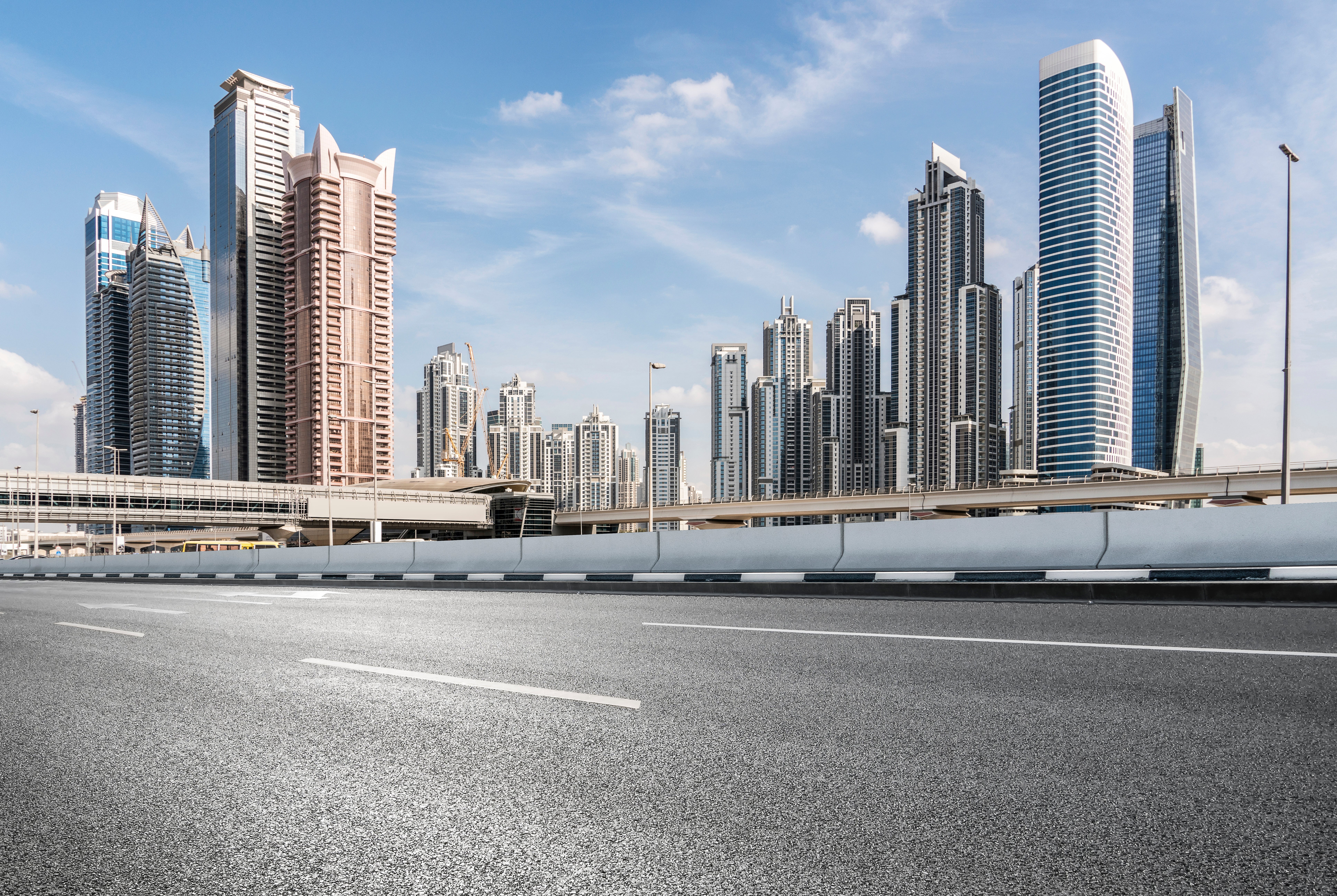 Skyline of modern skyscrapers successful a city, seen from an bare road, nether a bluish sky
