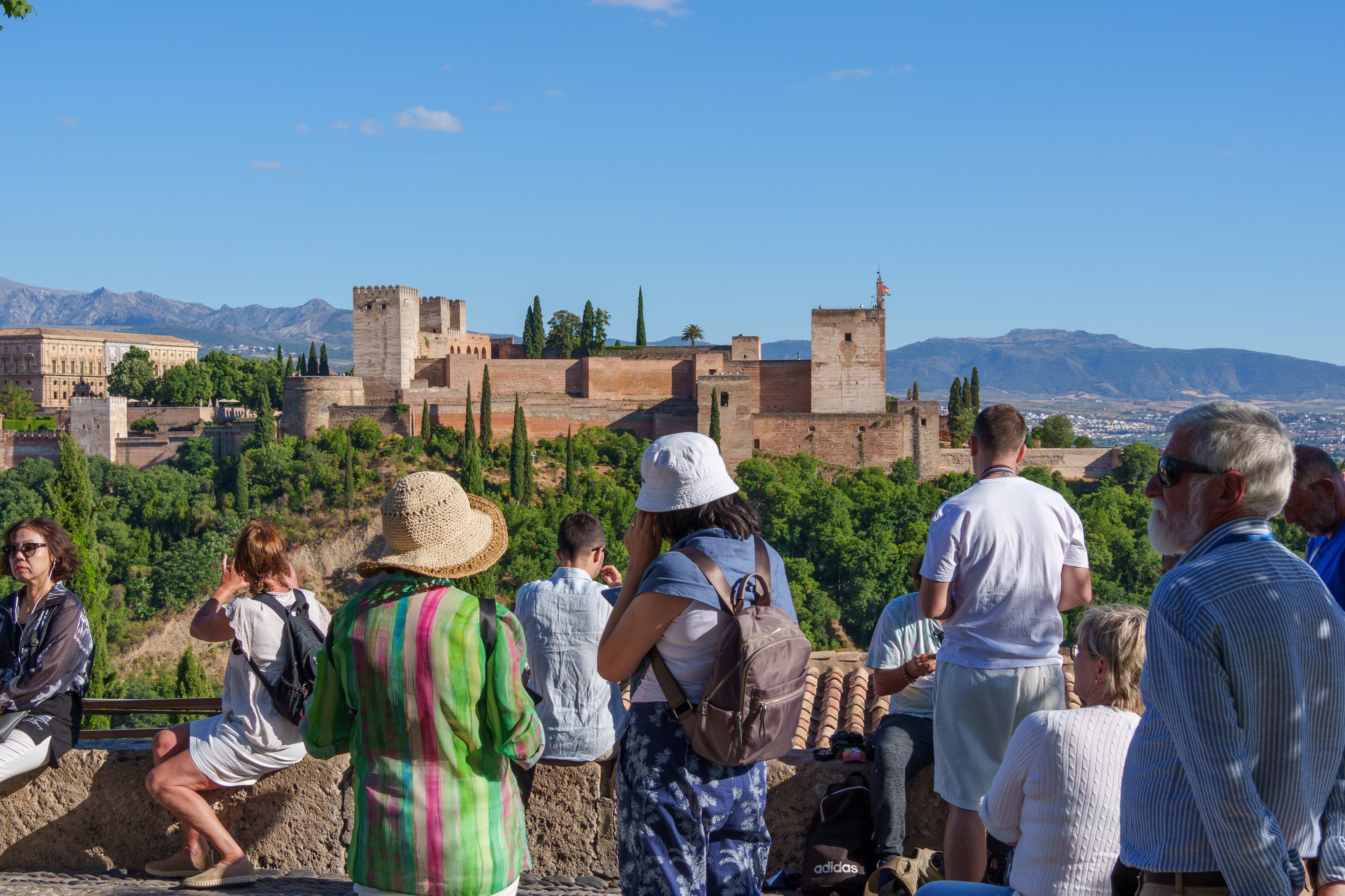 Tourists astatine a viewpoint overlooking the Alhambra successful Granada, Spain, with mountains successful the background