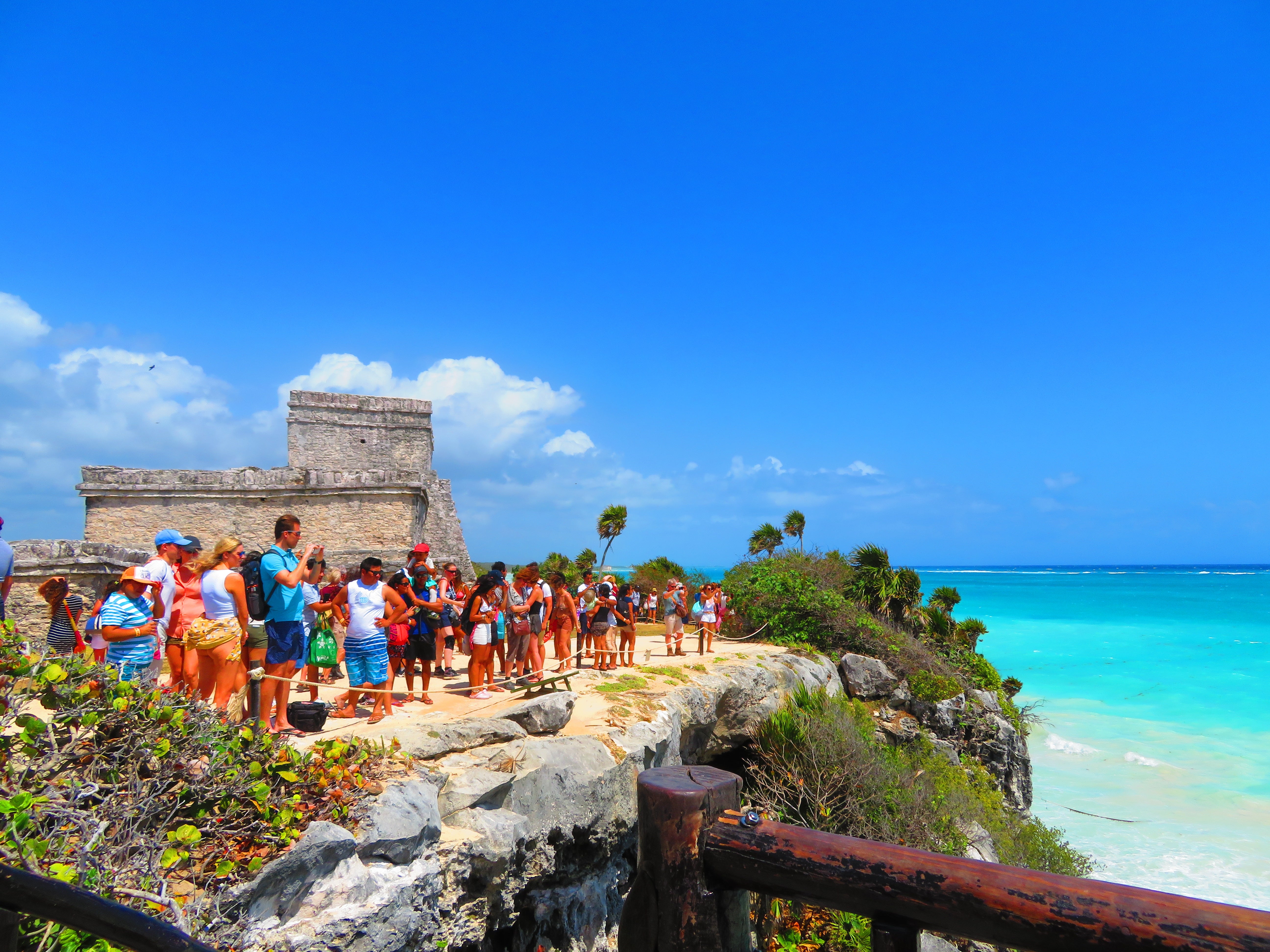 Tourists stitchery connected a cliff astatine Tulum Ruins, overlooking the Caribbean Sea with past chromatic operation and lush tropical plants successful view