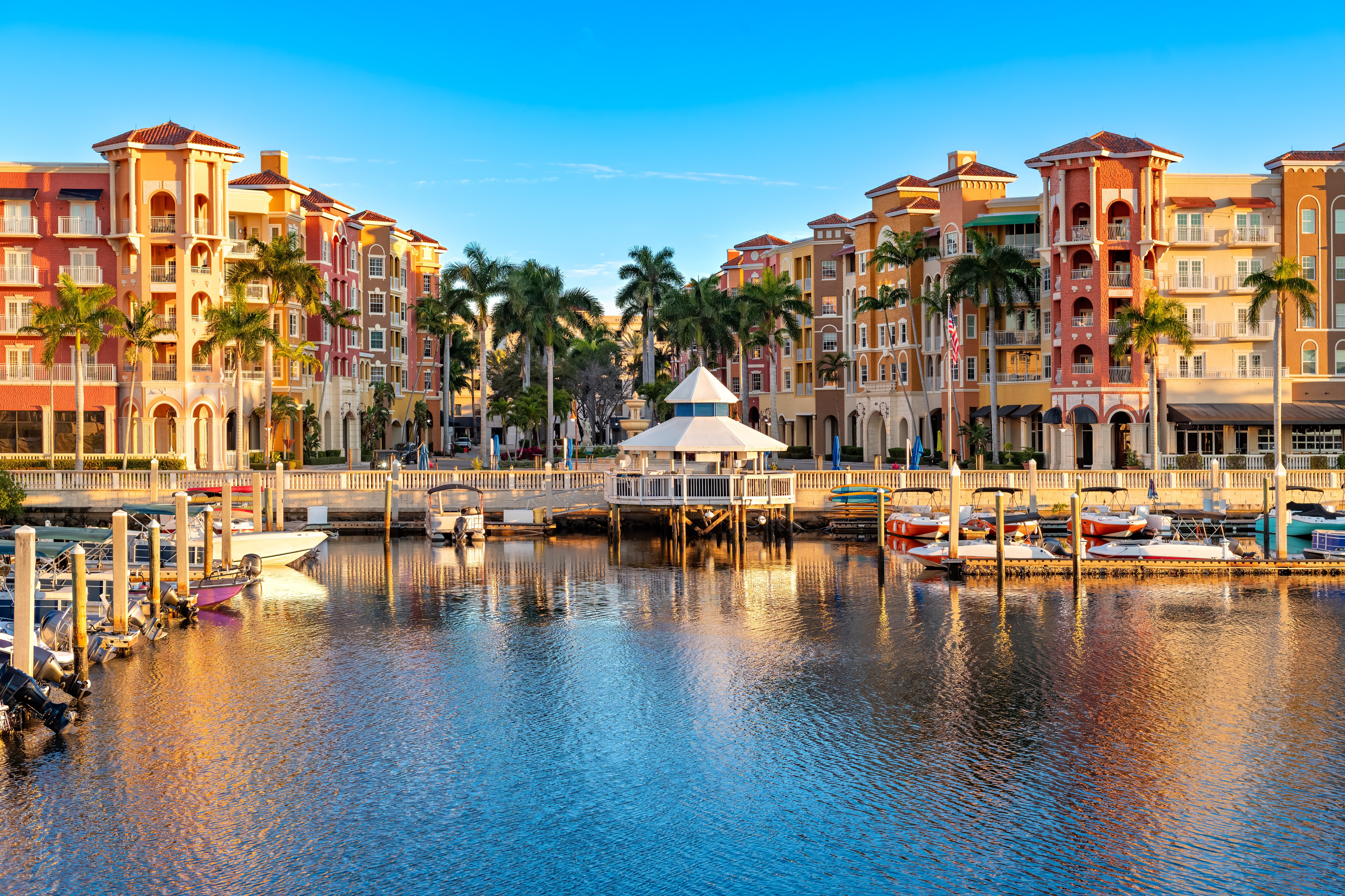 Scenic presumption of a waterfront country with multi-story buildings, thenar trees, boats docked astatine a marina, and a gazebo, acceptable against a wide sky