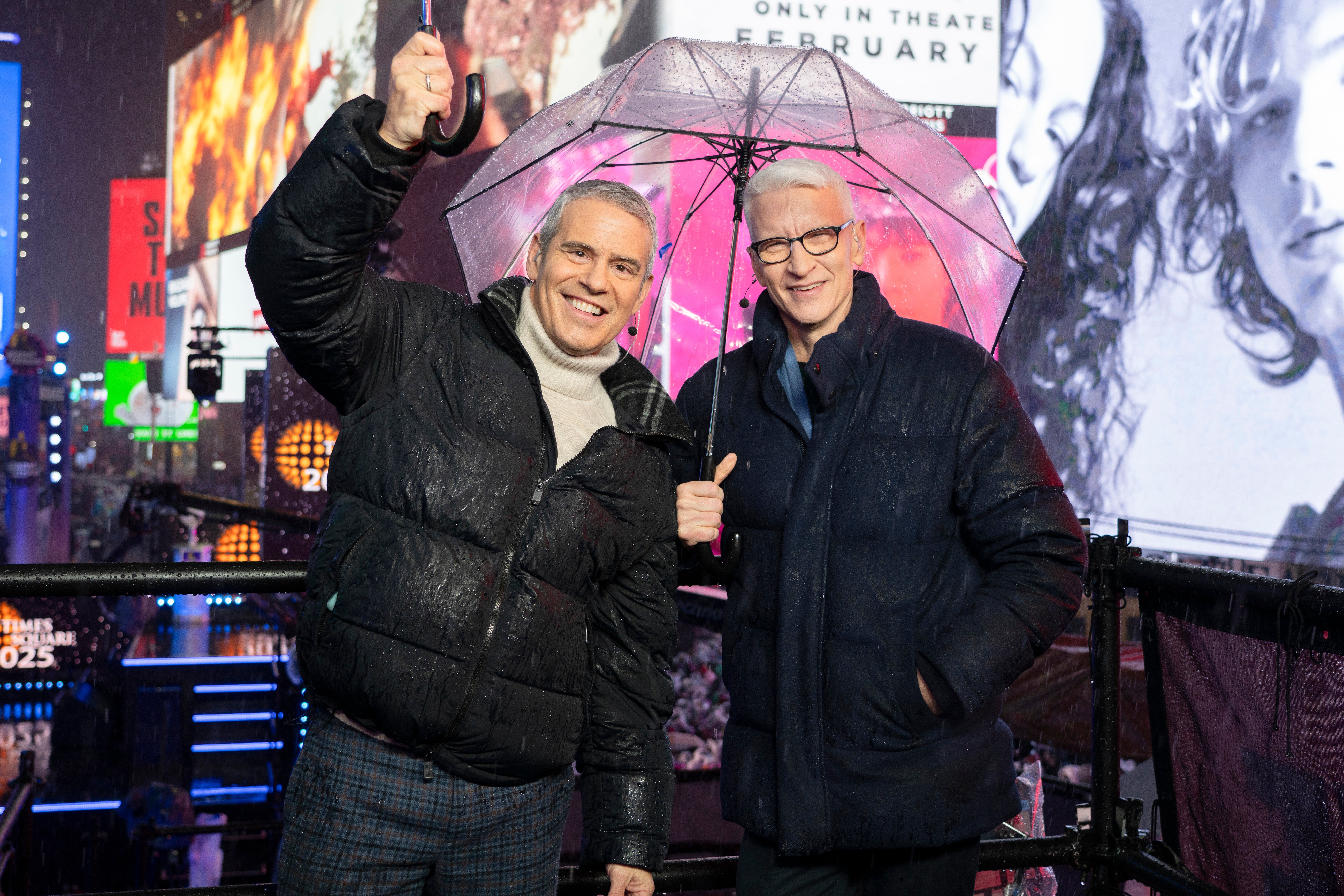 Two smiling men clasp a transparent umbrella successful a lively metropolis mounting astatine night, surrounded by agleam integer screens