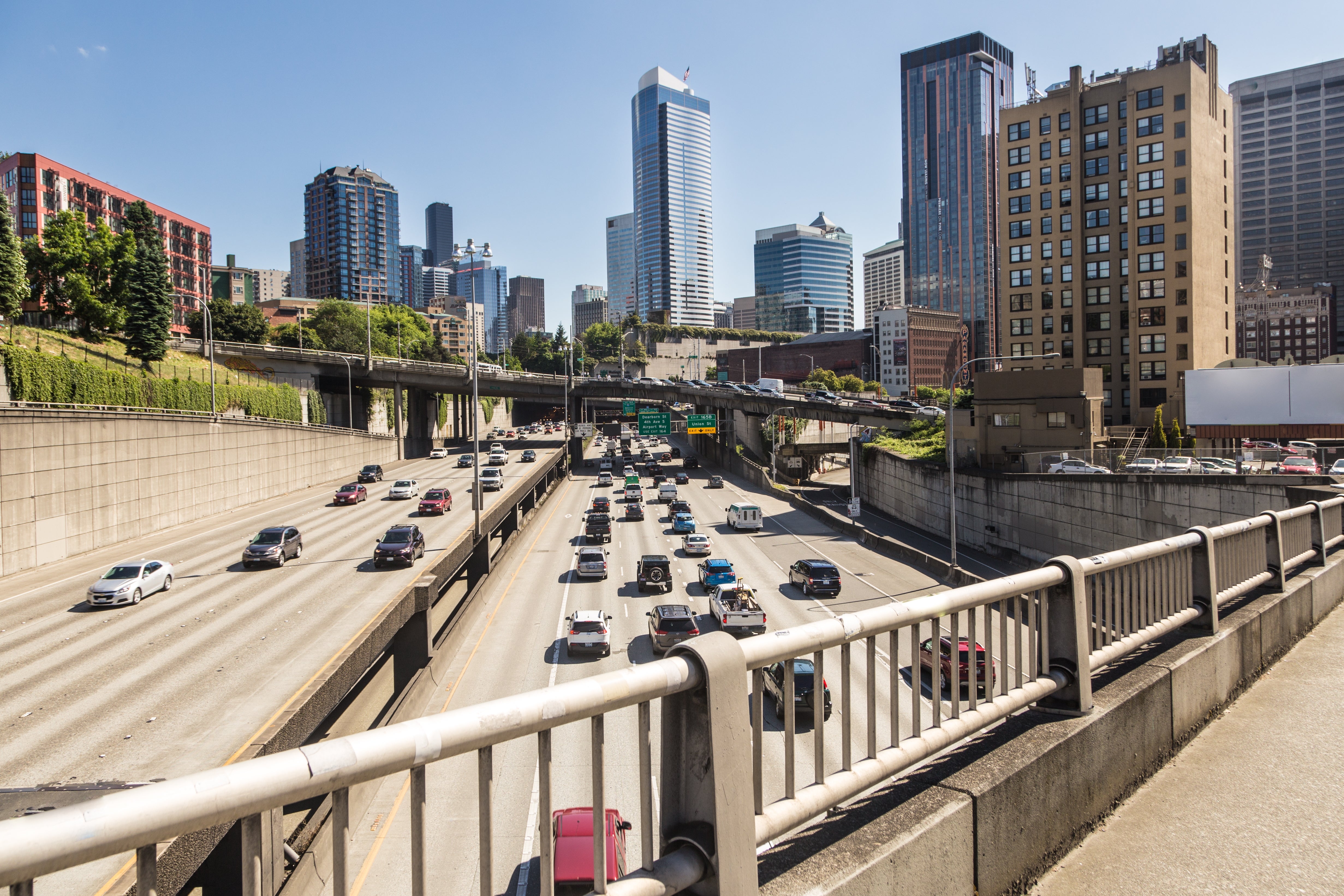 Urban road with galore cars, surrounded by gangly buildings and overpasses, nether a wide sky