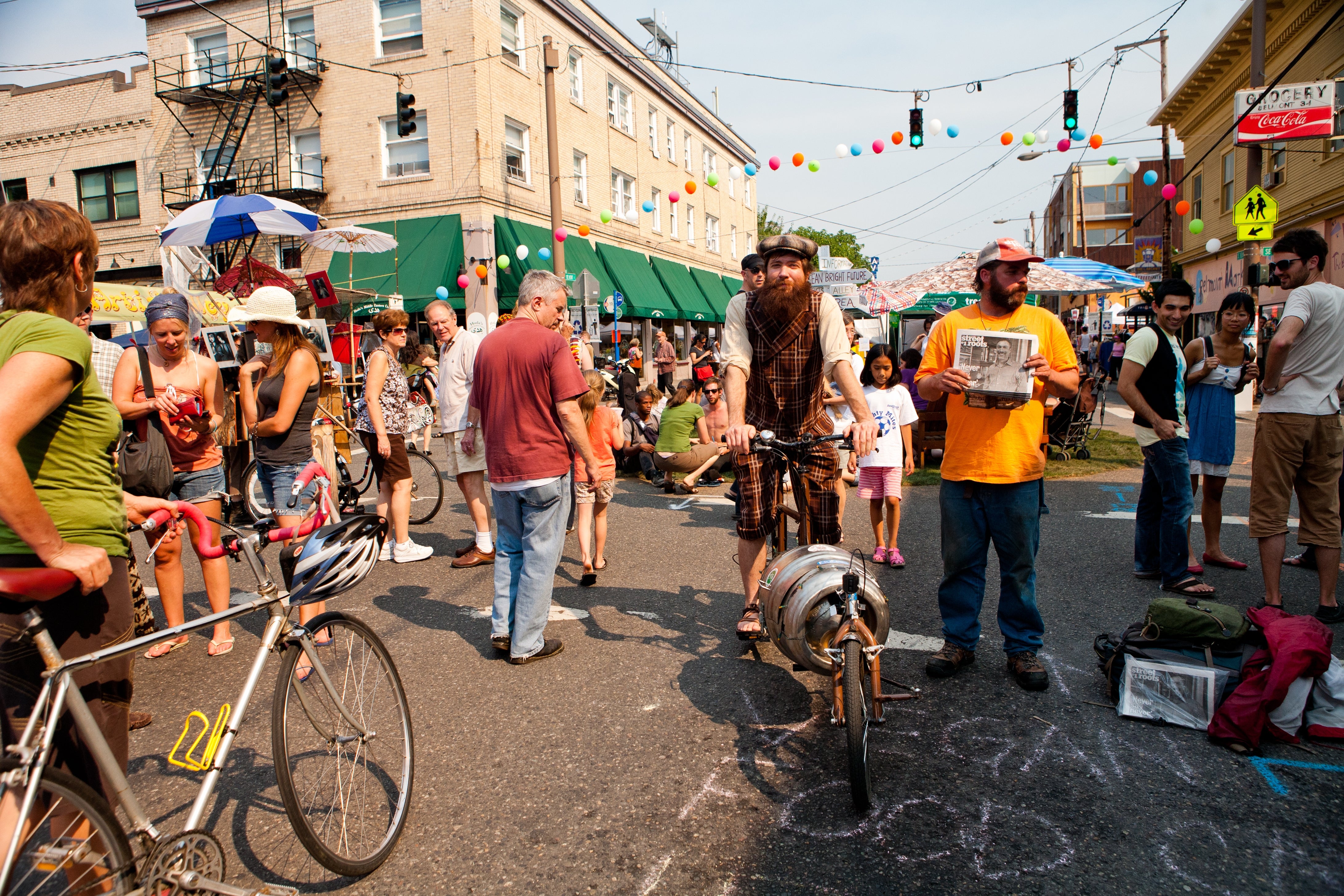 Outdoor thoroughfare festival with radical browsing stalls, a antheral with a agelong beard manages a unsocial motorcycle with a barrel, lively ambiance with colorful umbrellas