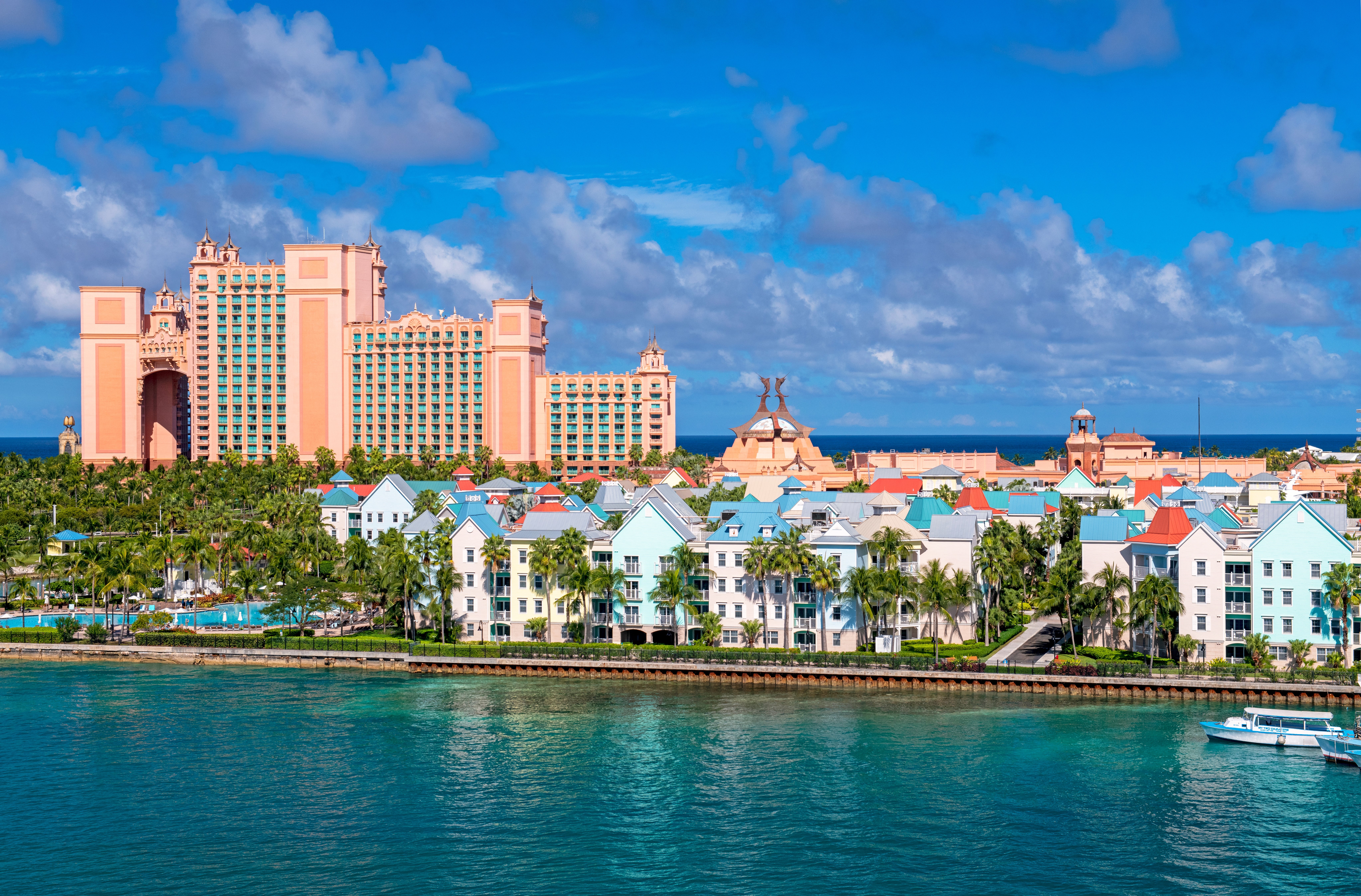 Resort buildings adjacent a tropical coastline with turquoise water, featuring a ample edifice analyzable successful the inheritance nether a partially cloudy sky