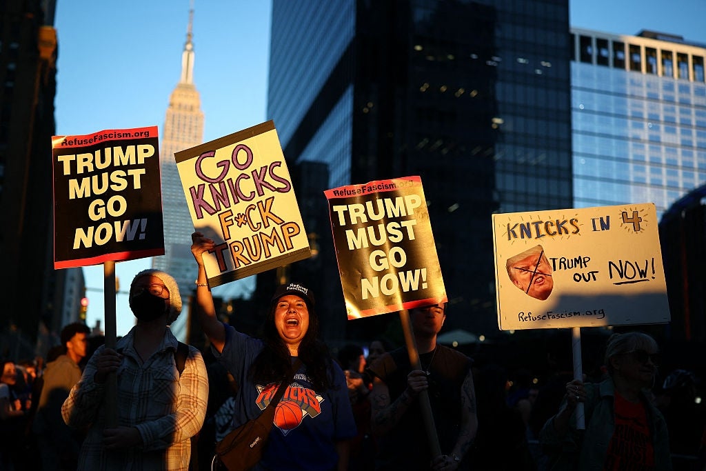 Demonstranter holder skilt mot Trump, med meldinger som