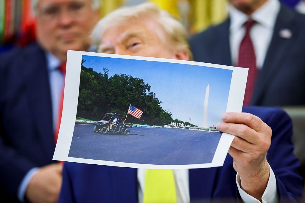 Person som holder et bilde av et lite kjøretøy med et amerikansk flagg foran Washington-monumentet under et møte