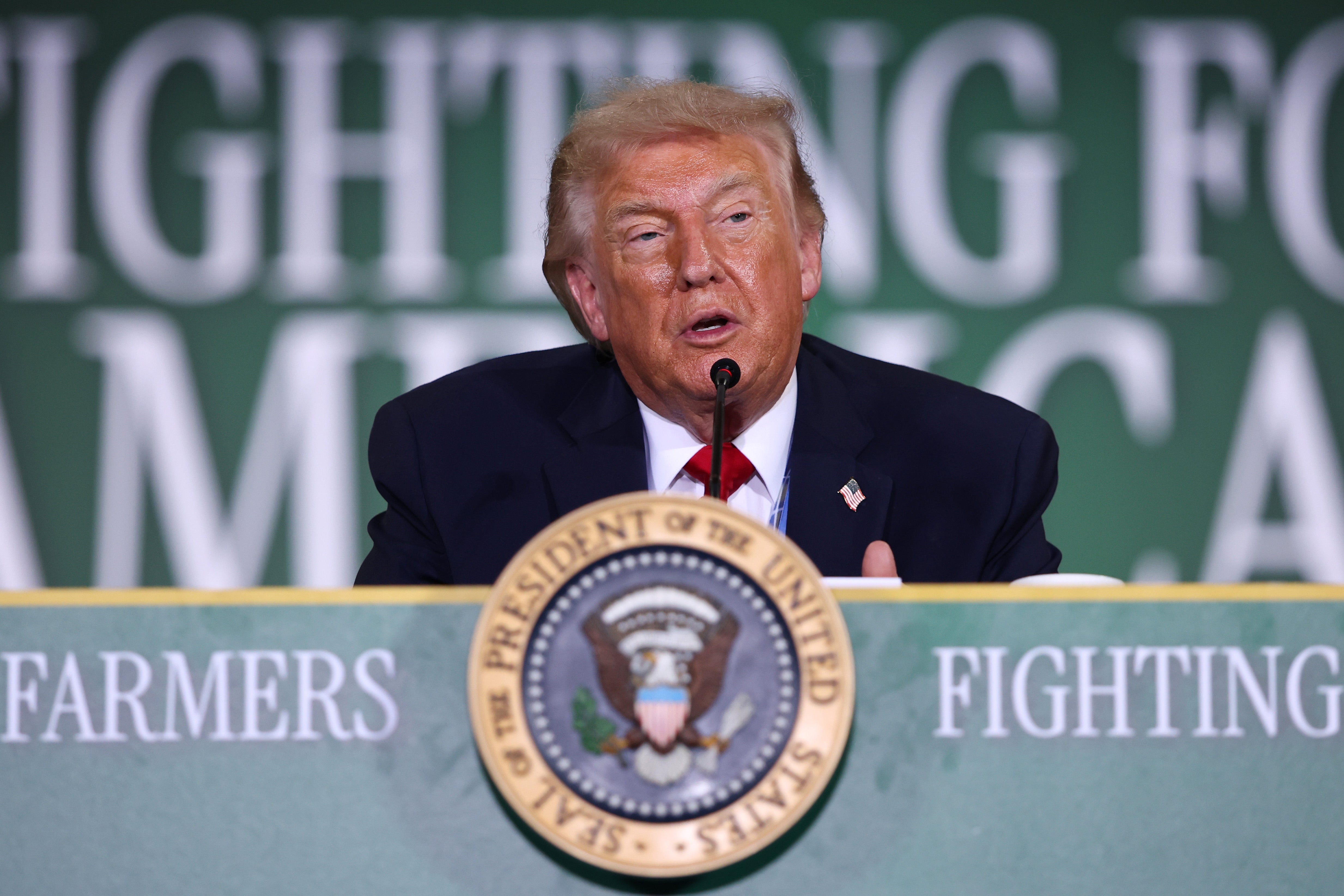Mann snakker på arrangement med «Fighting for Farmers»; og presidentsegl synlig