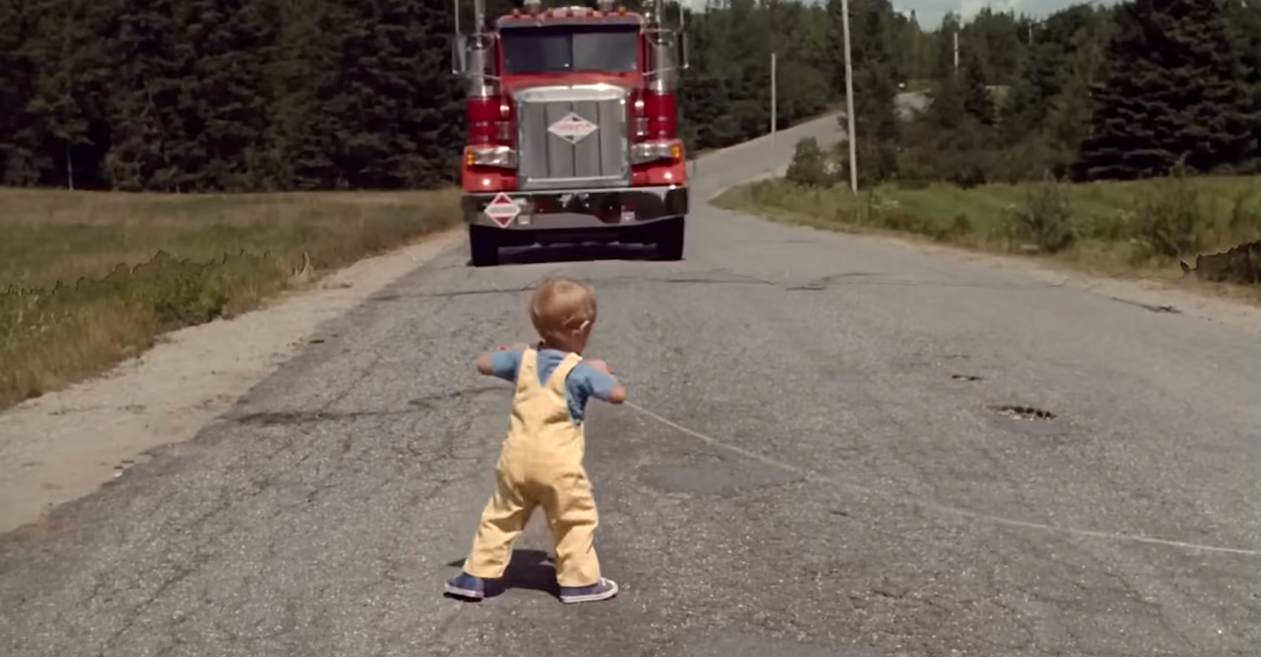 A toddler stands connected  a roadworthy  portion    picking up   a kite successful  beforehand   of an approaching truck