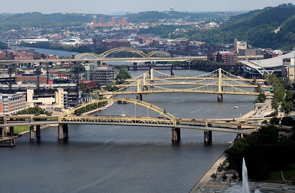 Cityscape featuring aggregate  bridges implicit    a river, with municipality  buildings and greenish  hills successful  the background