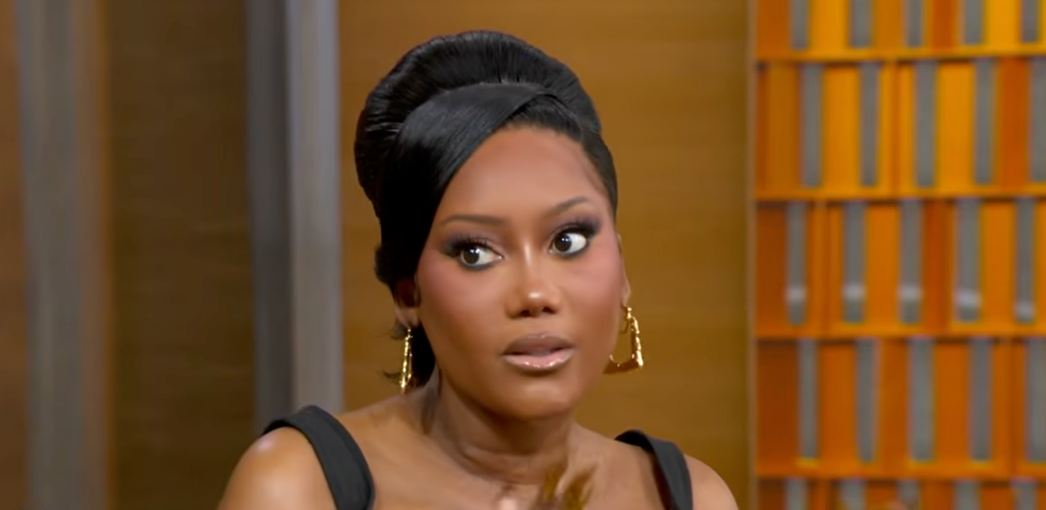 A idiosyncratic with an elegant updo hairstyle and hoop earrings, wearing a sleeveless top, appears to beryllium successful a speech connected a acceptable oregon show