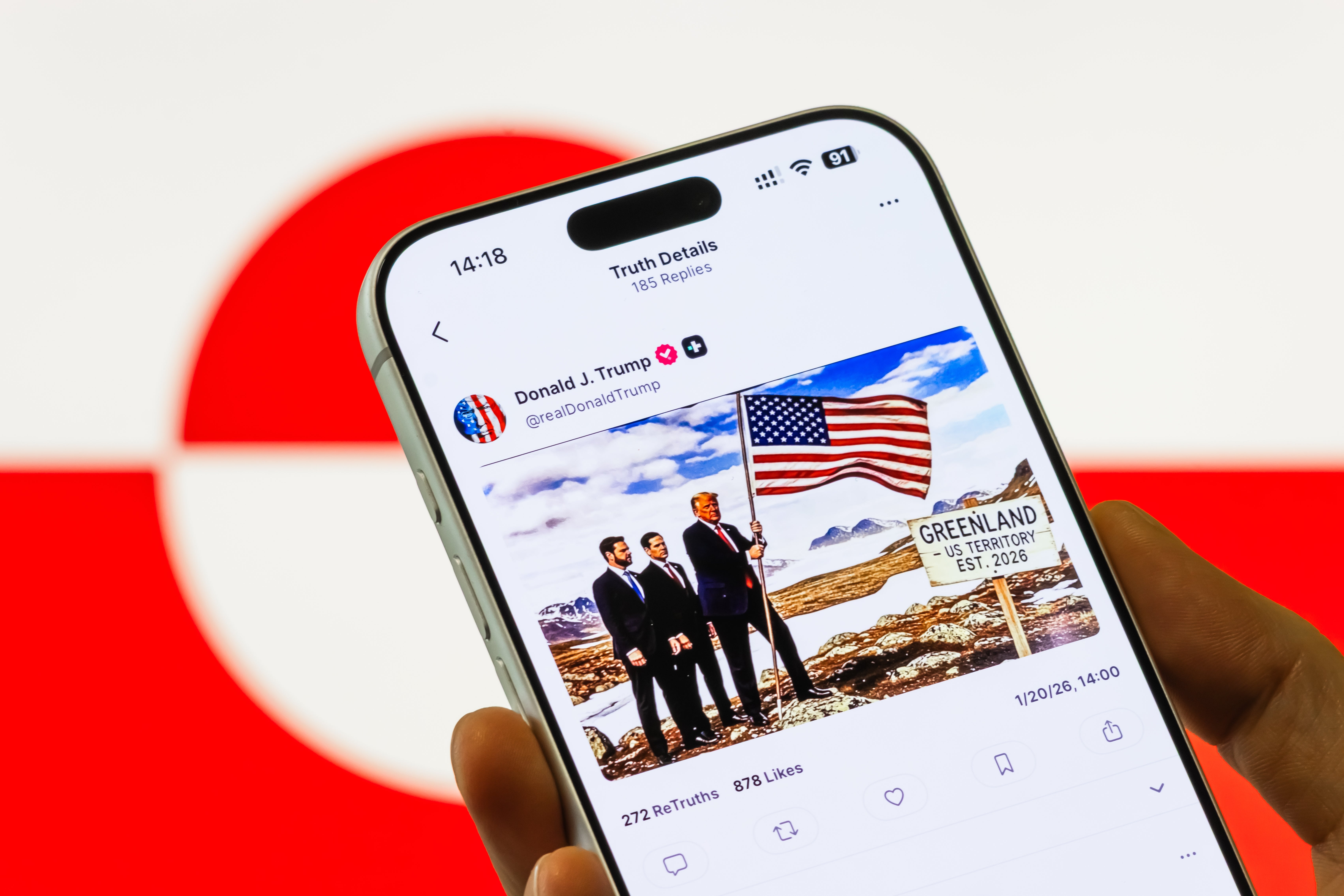 Person som holder en telefon som viser et redigert bilde av politiske personer med et amerikansk flagg på Grønland