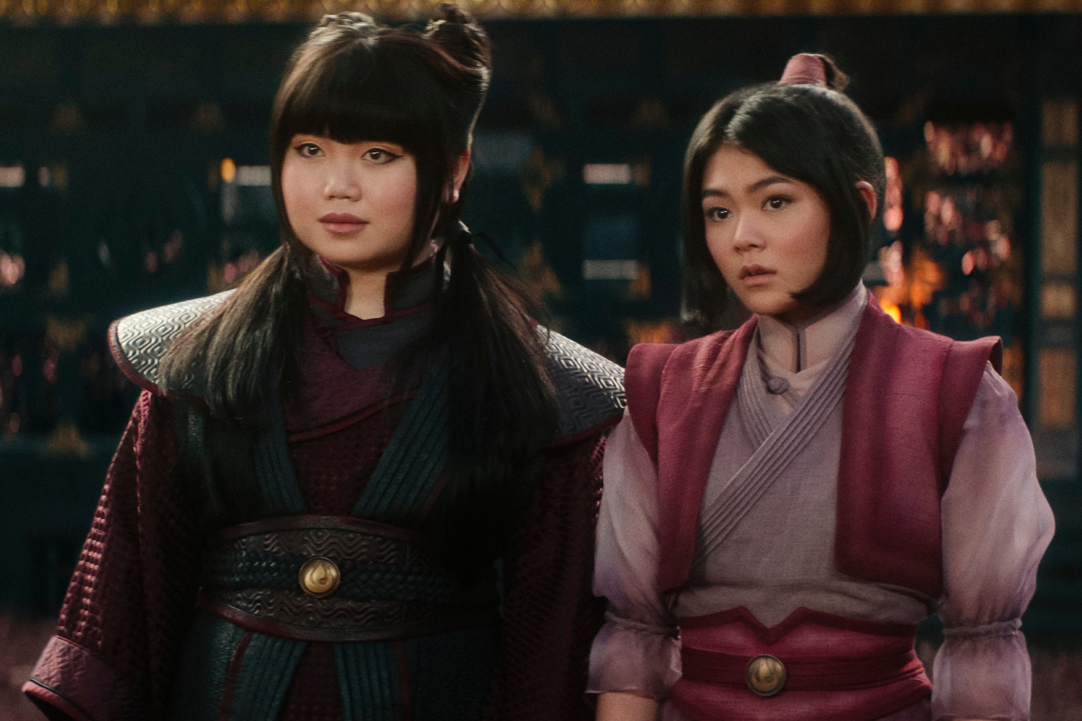 Two actors in medieval-inspired costumes stand in a cinematic setting, wearing armor and layered garments