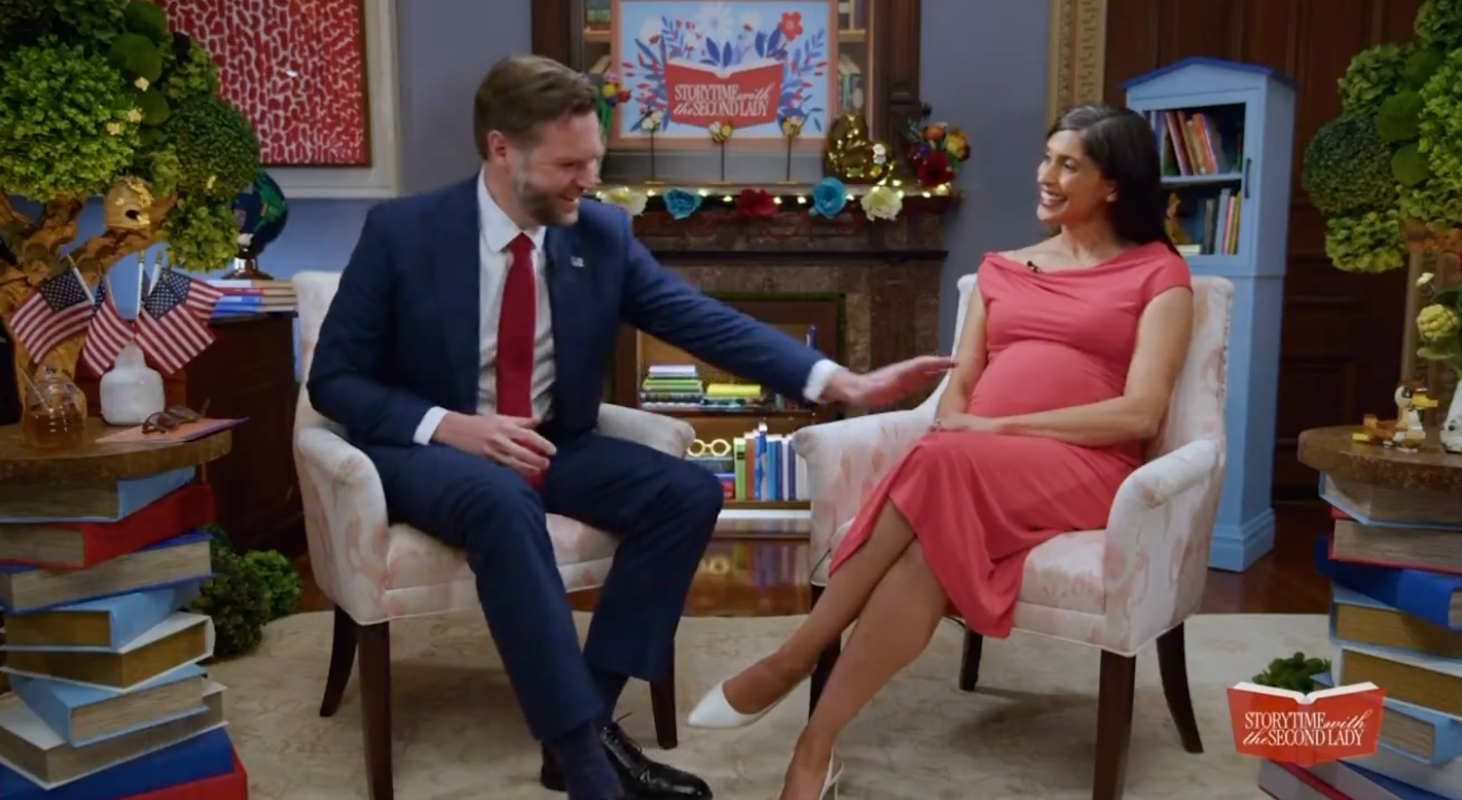 A antheral successful a suit and a large pistillate successful a reddish formal are sitting and chatting successful a decorated country with books and American-themed decor