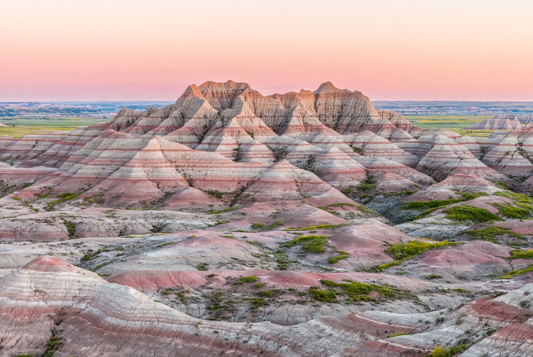 Layered stone  formations astatine  Badlands National Park during sunset, showcasing rugged terrain and distant   horizon