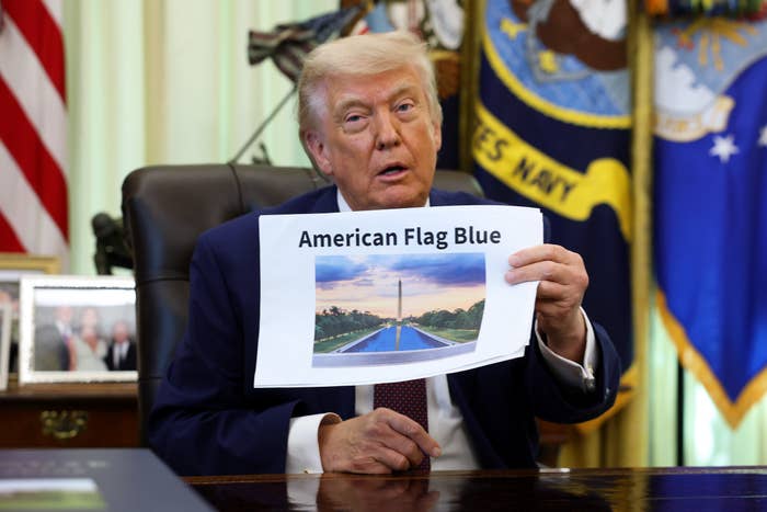 A idiosyncratic   successful  a suit   holds a insubstantial  showing a excavation  with the Washington Monument. The insubstantial  is labeled "American Flag Blue."