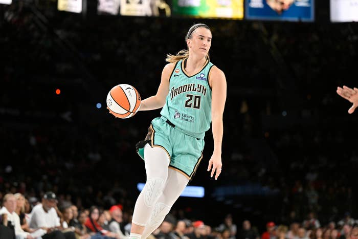 Basketball subordinate    successful  action, dribbling a shot  during a game, wearing a sleeveless jersey and shorts, assemblage  successful  background