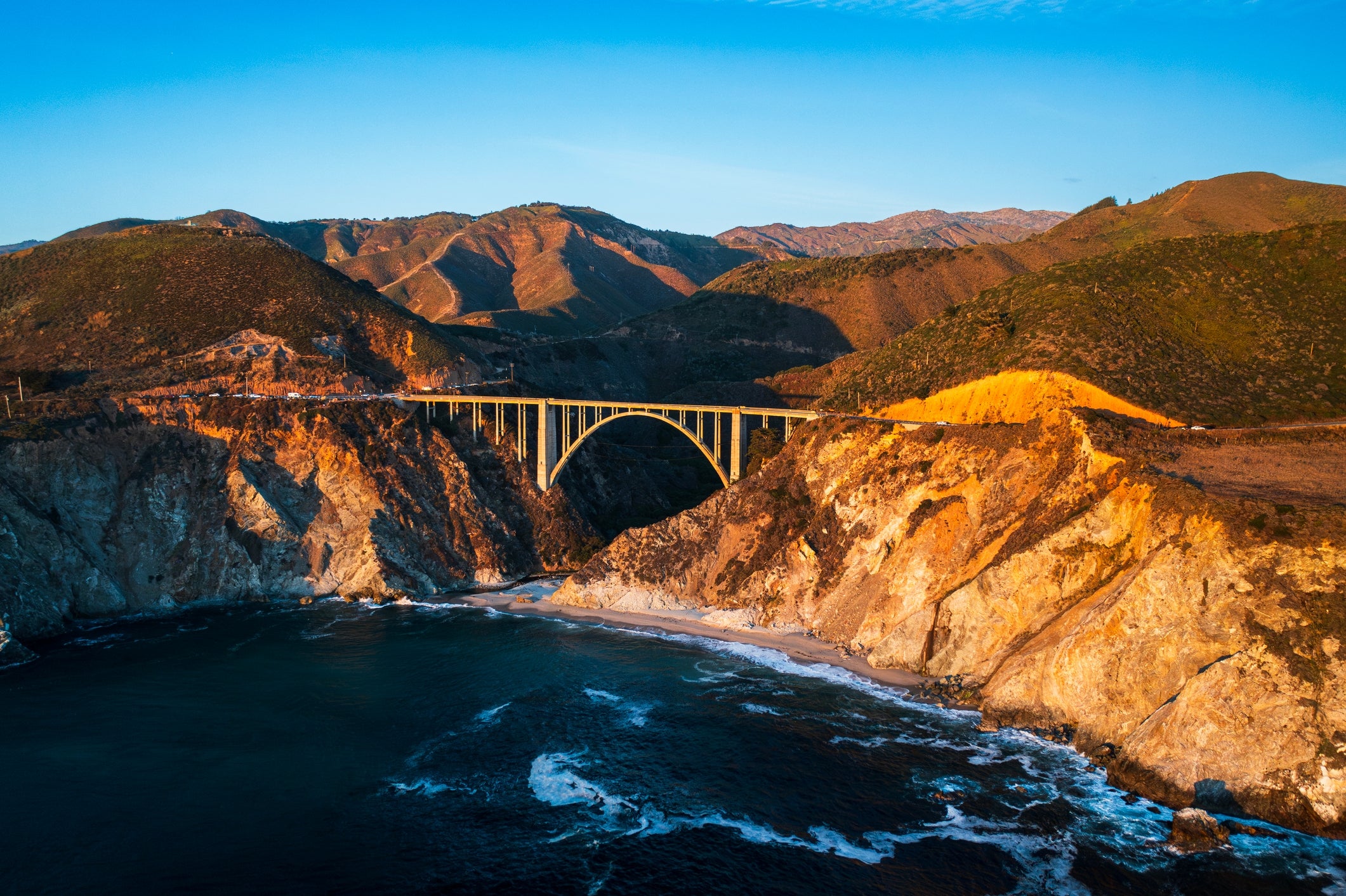 Bridge spanning a rocky coastline with waves, surrounded by mountains successful  a scenic coastal landscape
