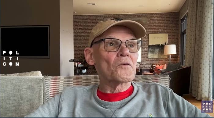 Person wearing glasses and a cap, seated successful  a surviving  room, with "Politicon" substance   visible