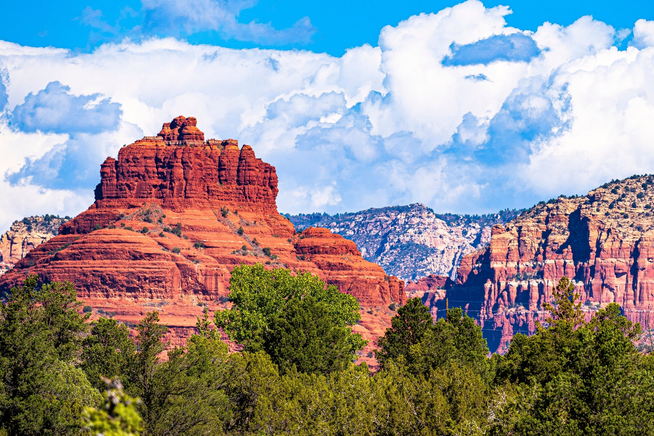 A majestic scenery  featuring reddish  stone  formations and lush greenery nether  a cloudy sky