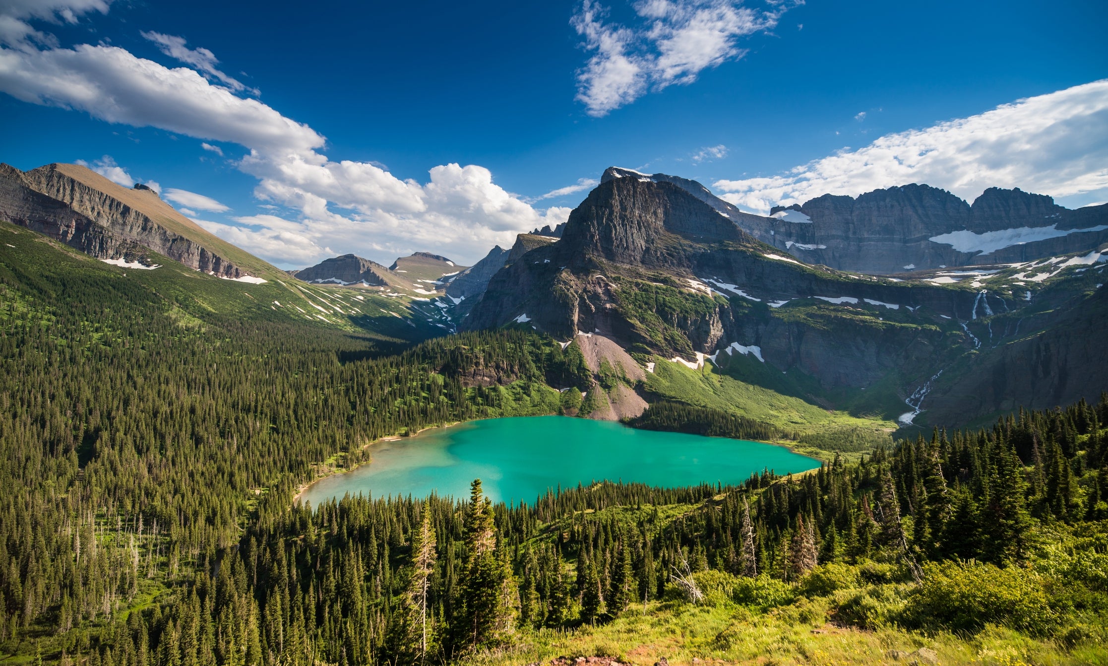 Scenic upland  scenery  with a water  surrounded by lush wood  and rugged peaks nether  a agleam  sky