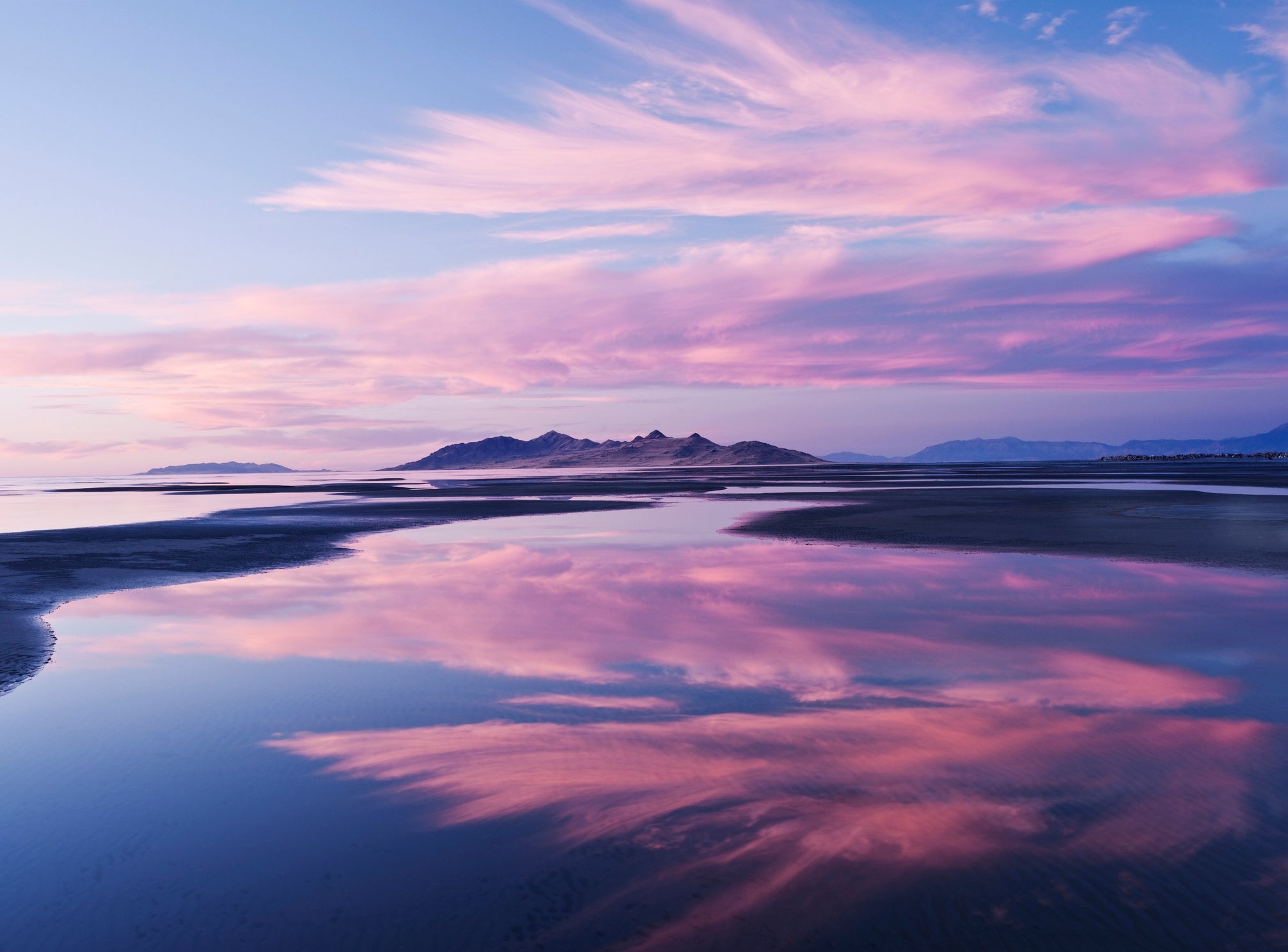 Scenic presumption    of h2o  reflecting a melodramatic  entity  with wispy clouds and distant   mountains connected  the horizon