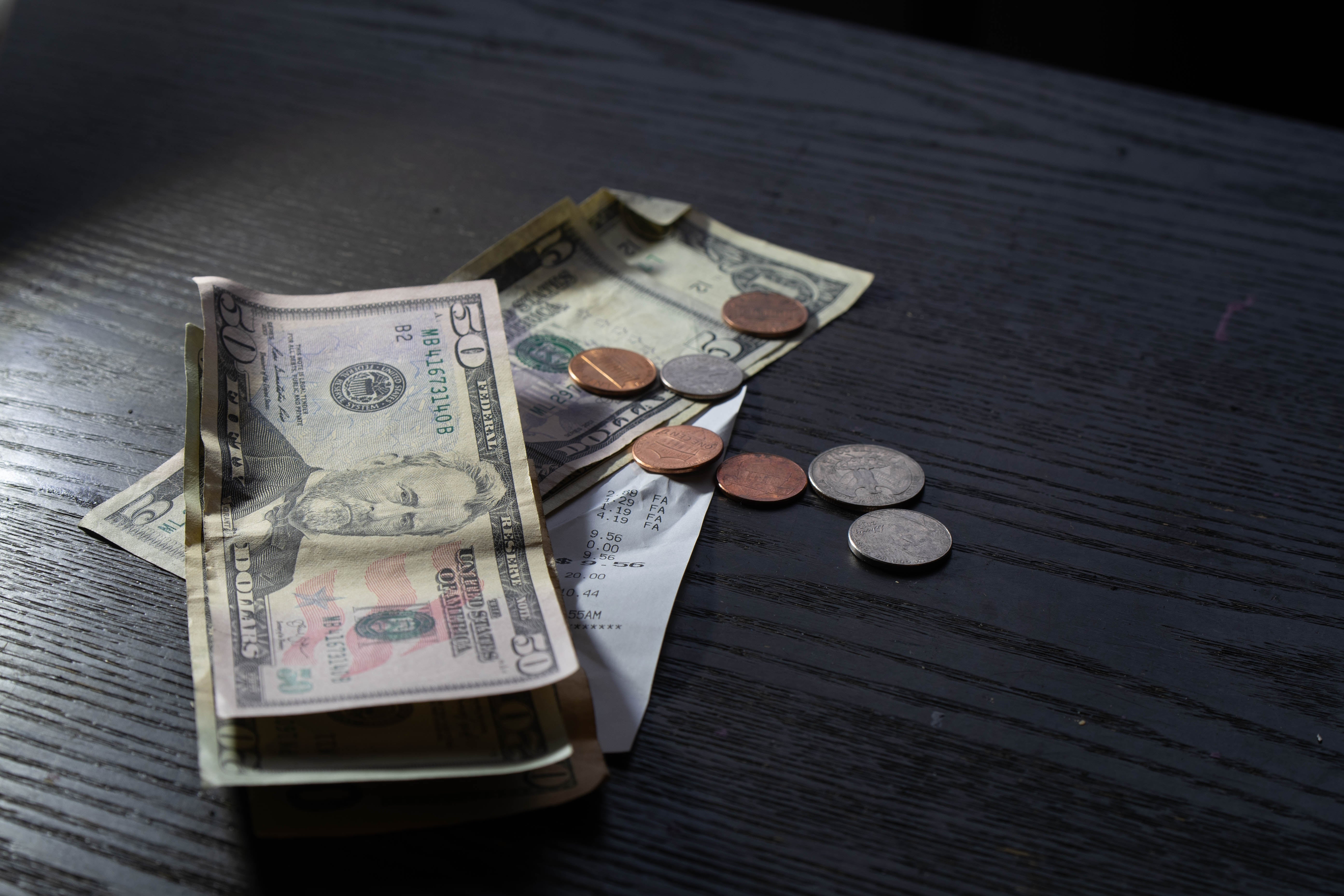 Cash and coins connected  a table, including 20 and 10 dollar bills and assorted coins, adjacent  to a receipt
