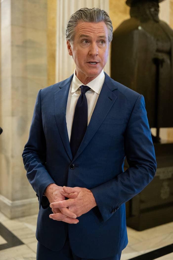 Man successful  a bluish  suit   and necktie  speaks, with a ceremonial  mounting  successful  the background