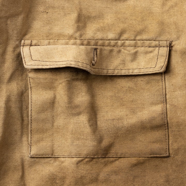 Close-up of a brown fabric pocket on a garment with visible stitching detail