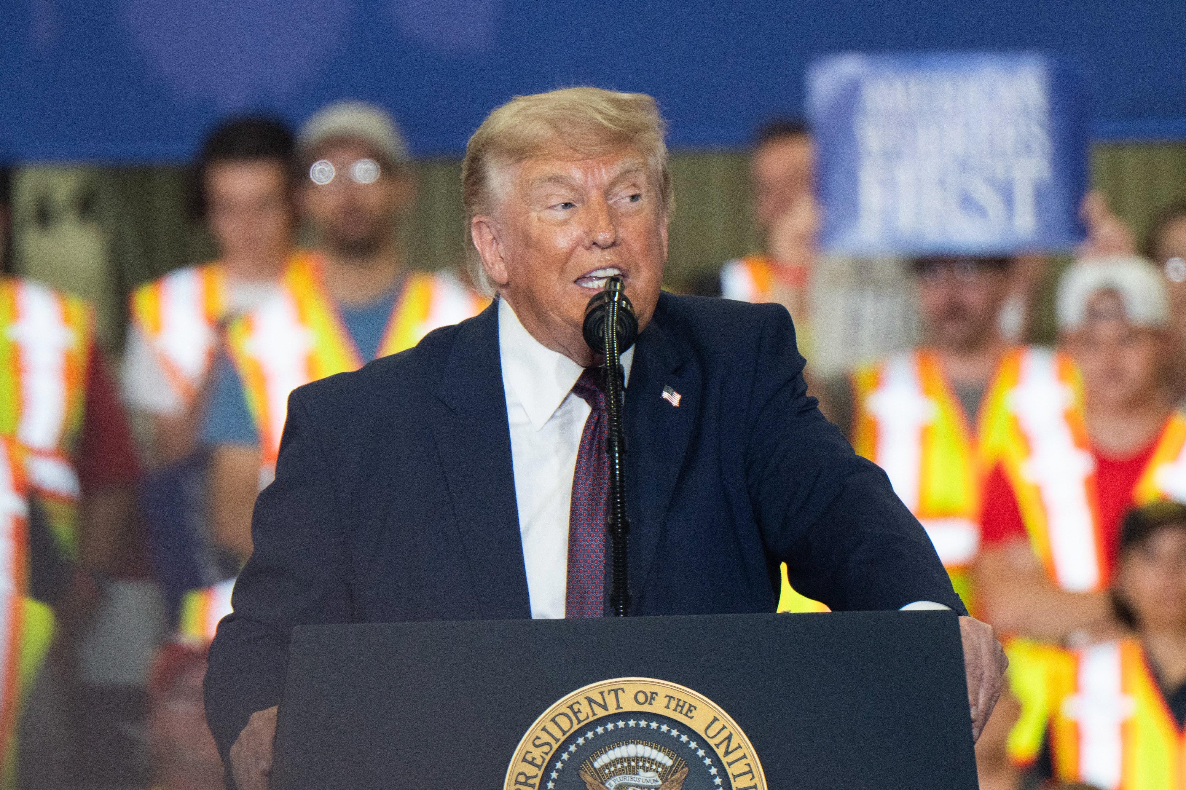 A idiosyncratic   speaking astatine  a podium with a seal, wearing a suit, successful  beforehand   of a assemblage  wearing information   vests