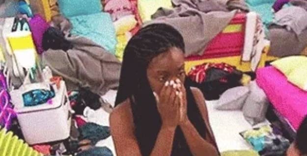 A idiosyncratic   stands successful  a cluttered room, looking amazed  with hands covering their mouth
