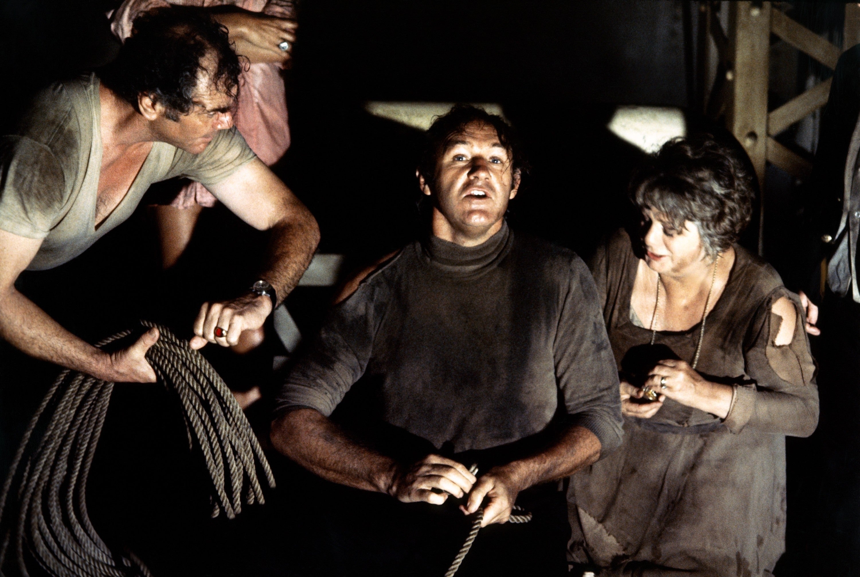 Three radical   successful  rugged, distressed covering  look   upwards with tense expressions, holding ropes, suggesting a melodramatic  oregon  aggravated  scene