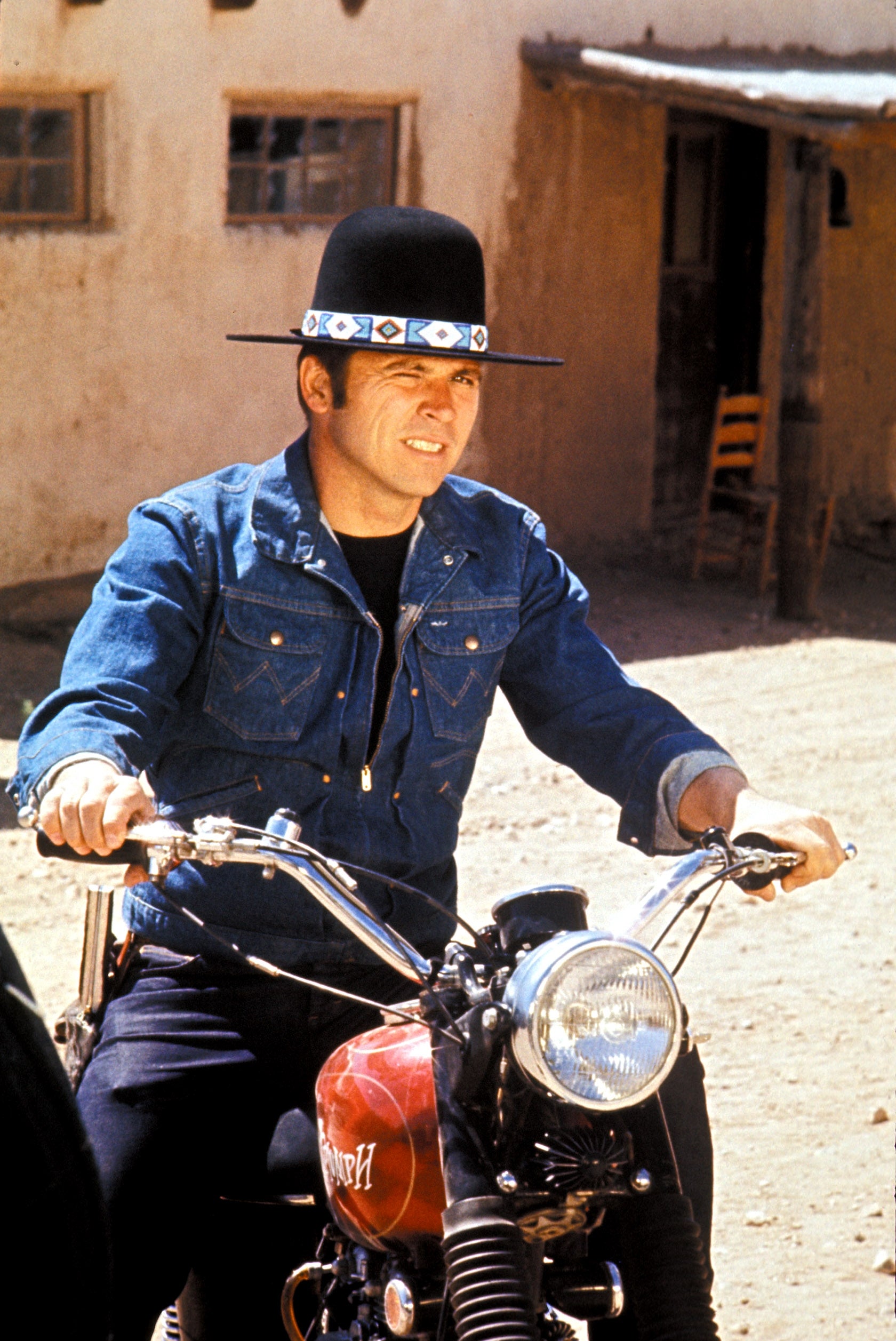 Person successful  a denim overgarment   and wide-brimmed chapeau  riding a motorcycle outdoors