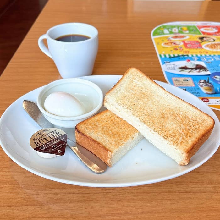 ココス「【単品メニュー】トースト ゆで玉子付き」の全体的な様子。トースト、ゆで卵、バターが乗った皿とコーヒーが見える。
