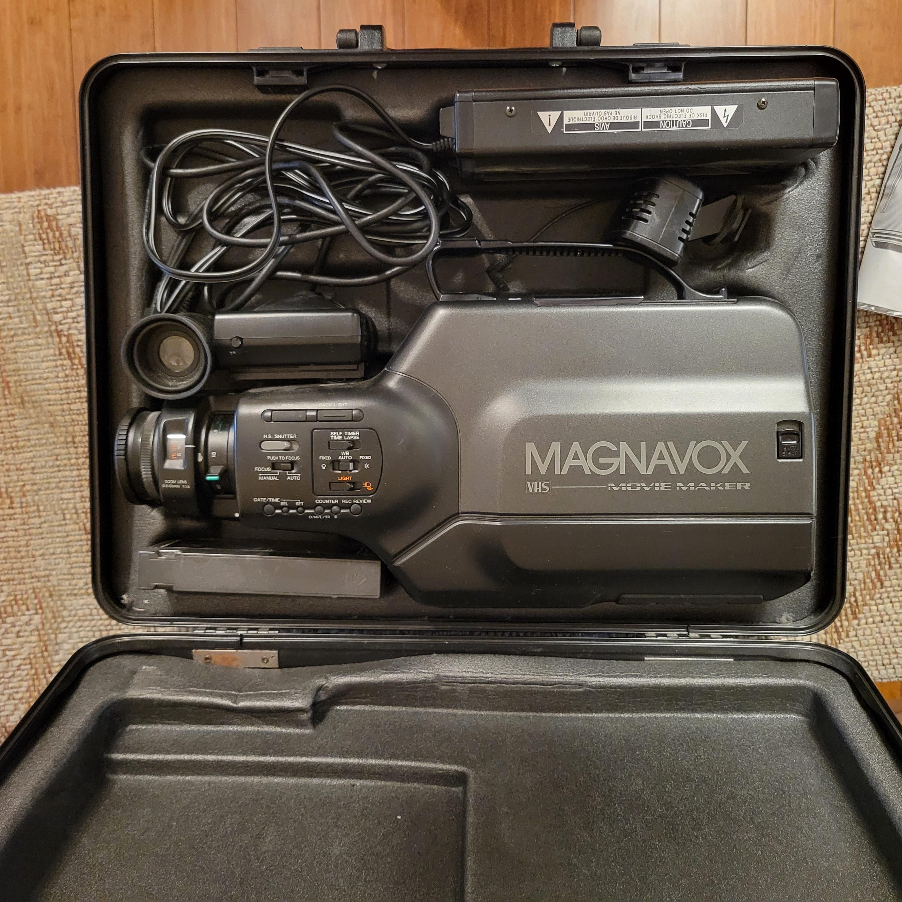 Vintage Magnavox video camera in an open black case with cables and a manual