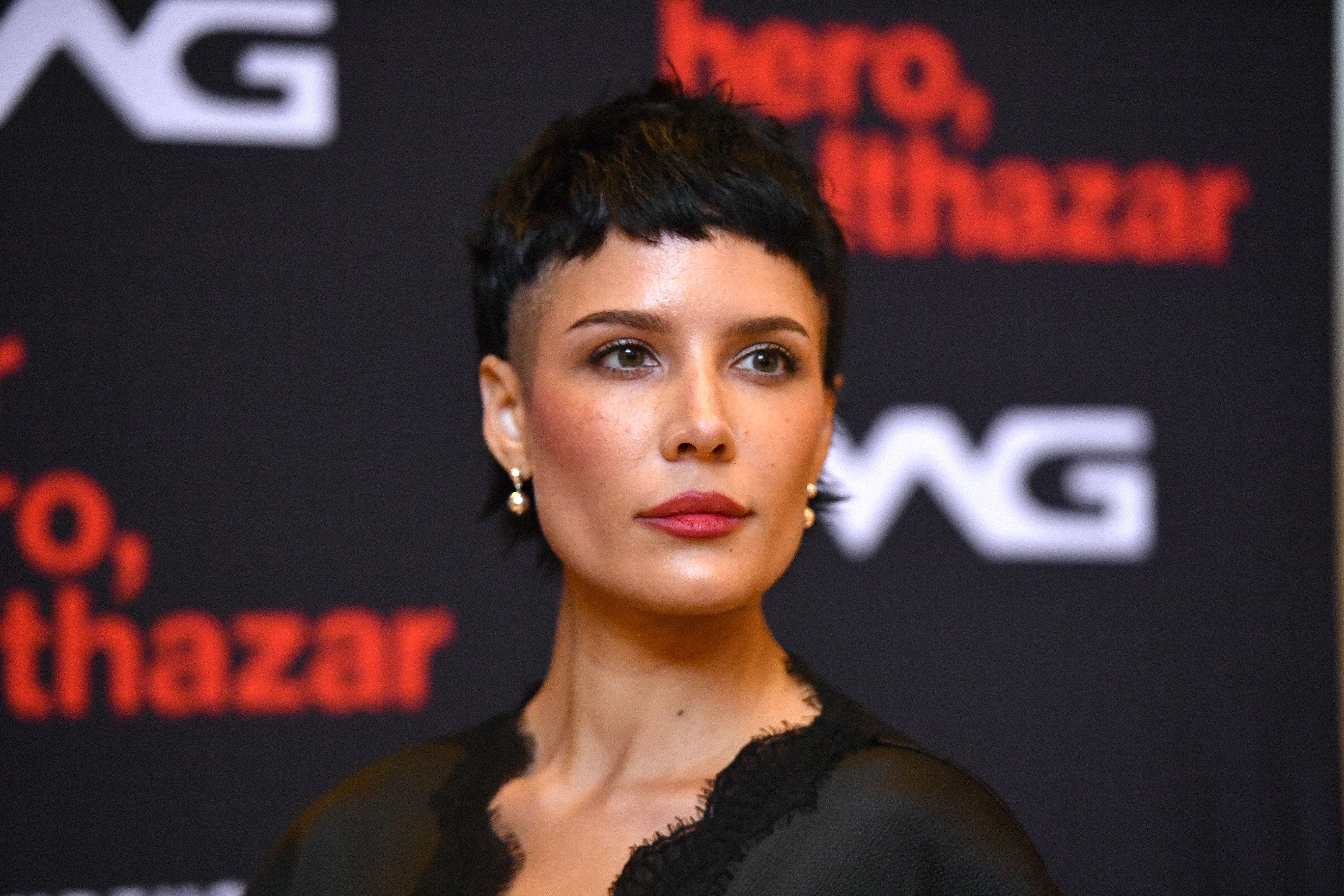 Halsey with short, styled hair attends a red carpet event, wearing elegant attire