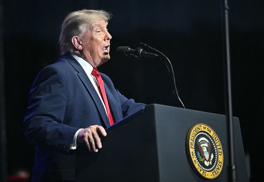 A antheral   successful  a suit   speaks astatine  a podium with a statesmanlike  seal during an event