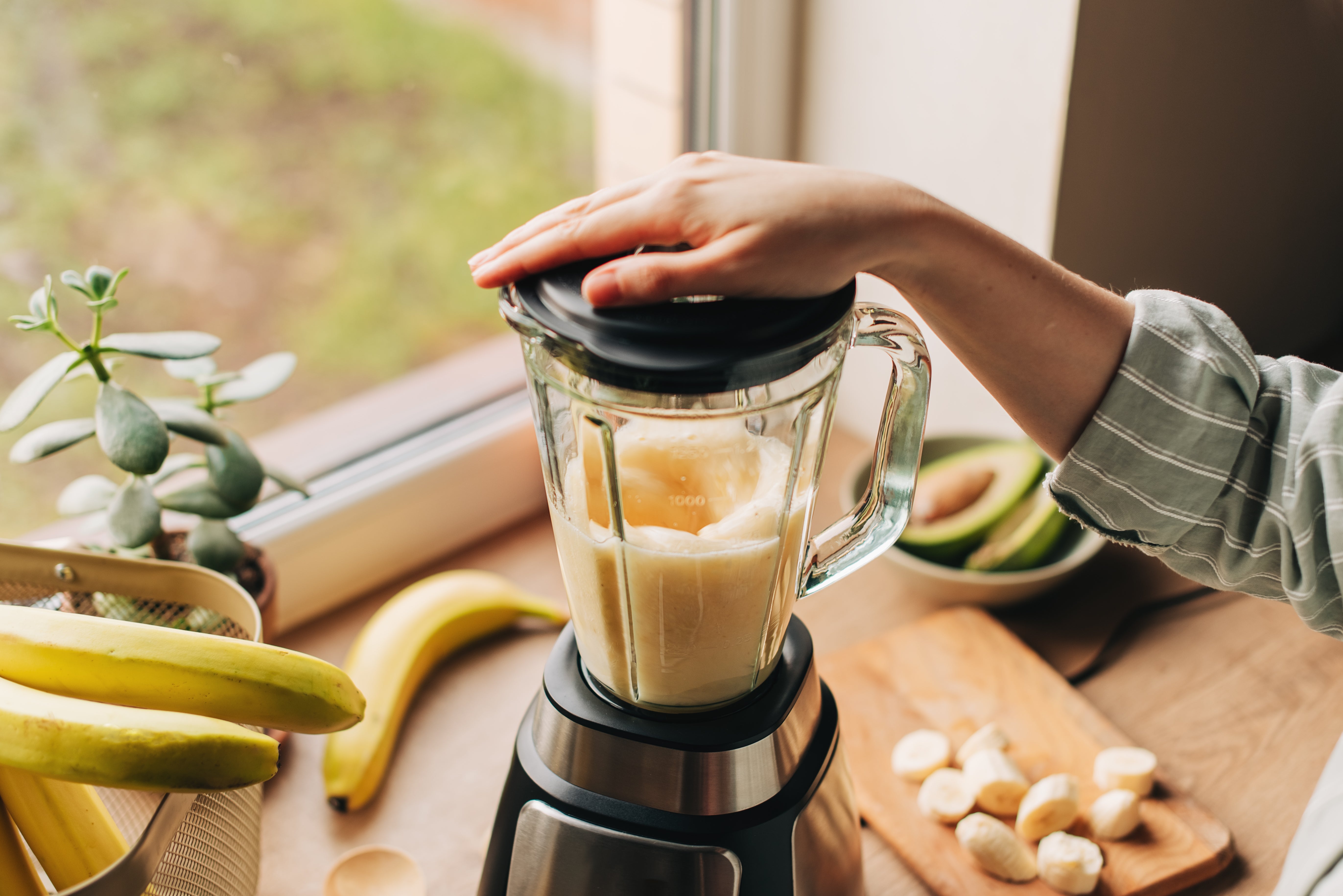 A idiosyncratic   operates a blender filled with bananas, adjacent   a model   with much  bananas and sliced effect   connected  the counter