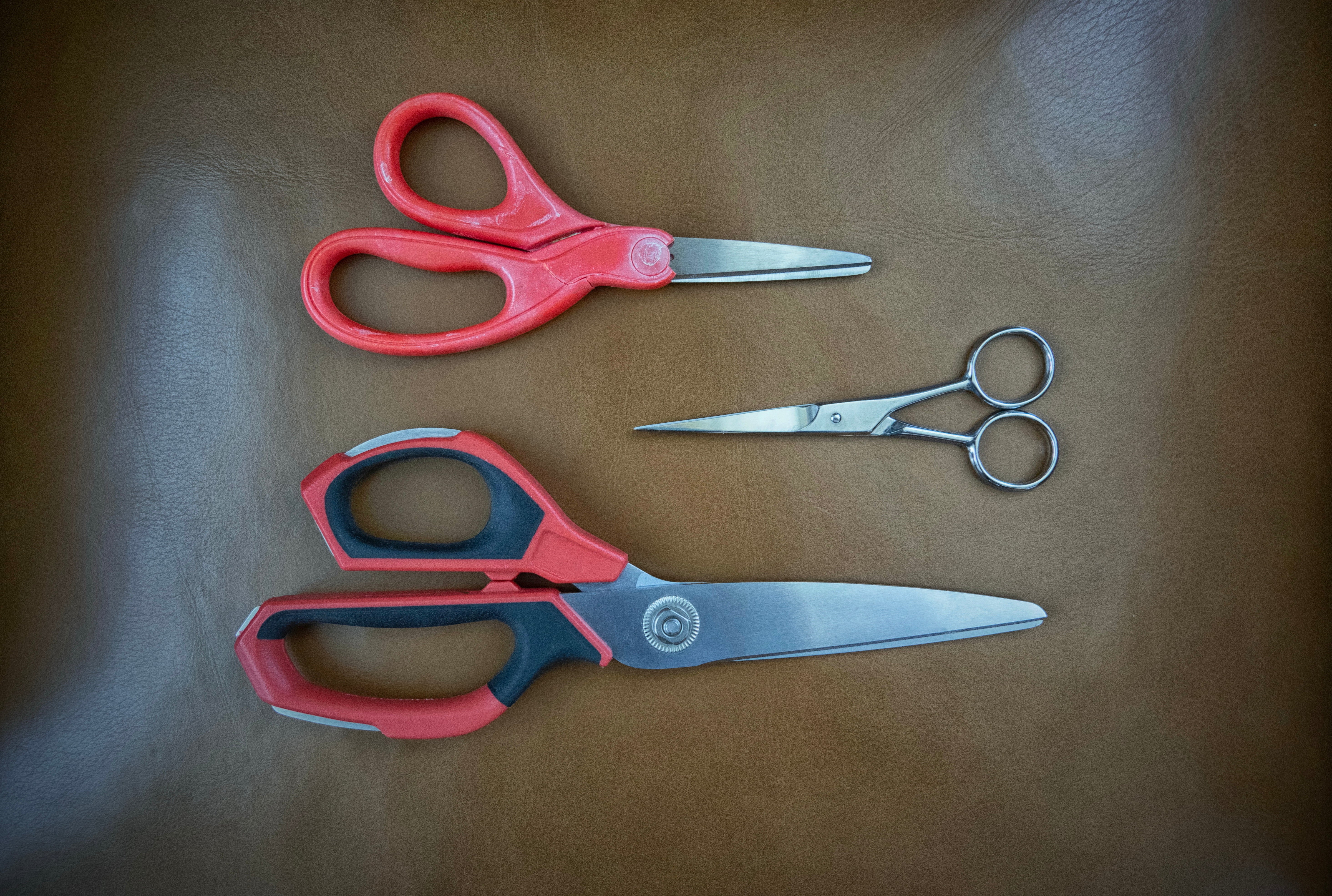 Three pairs of scissors of antithetic  sizes and designs placed connected  a surface