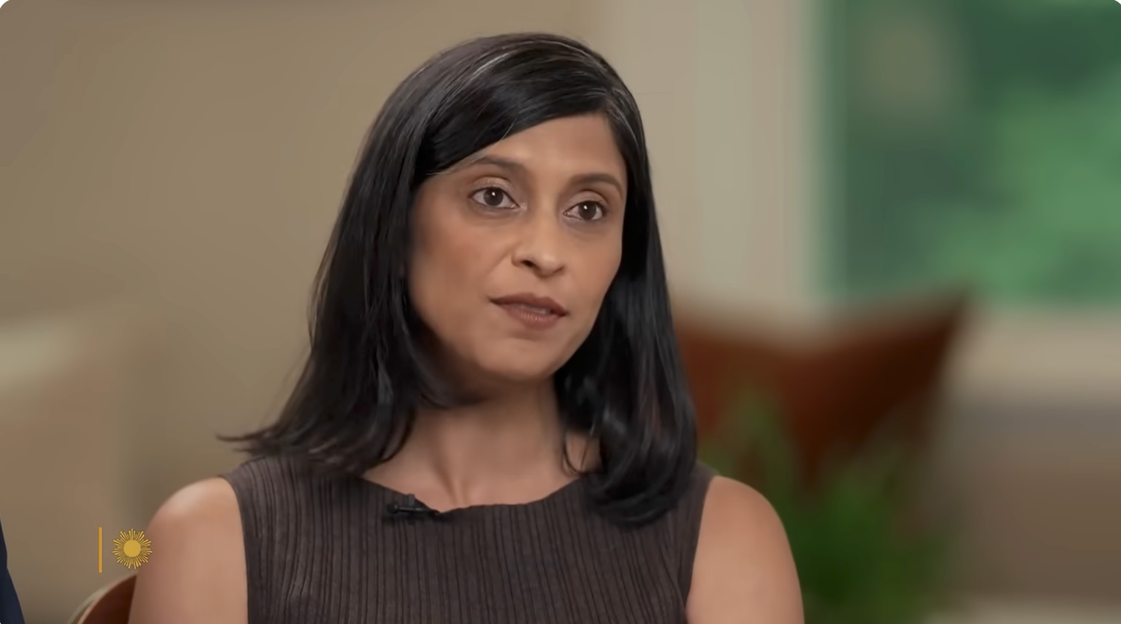 Person being interviewed, sitting indoors, speaking with a superior   expression