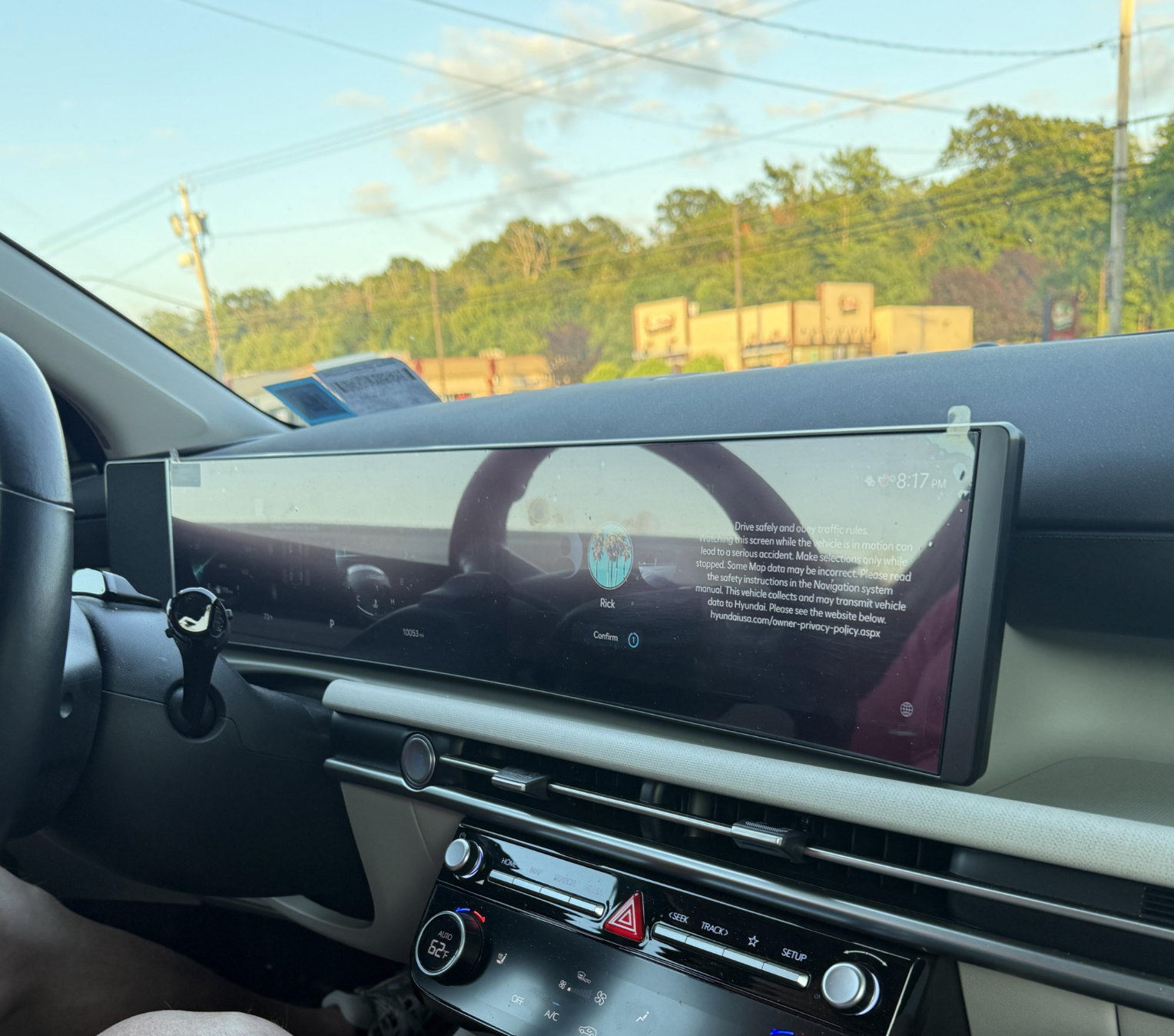 Car interior showing a wide dashboard screen with navigation and music controls