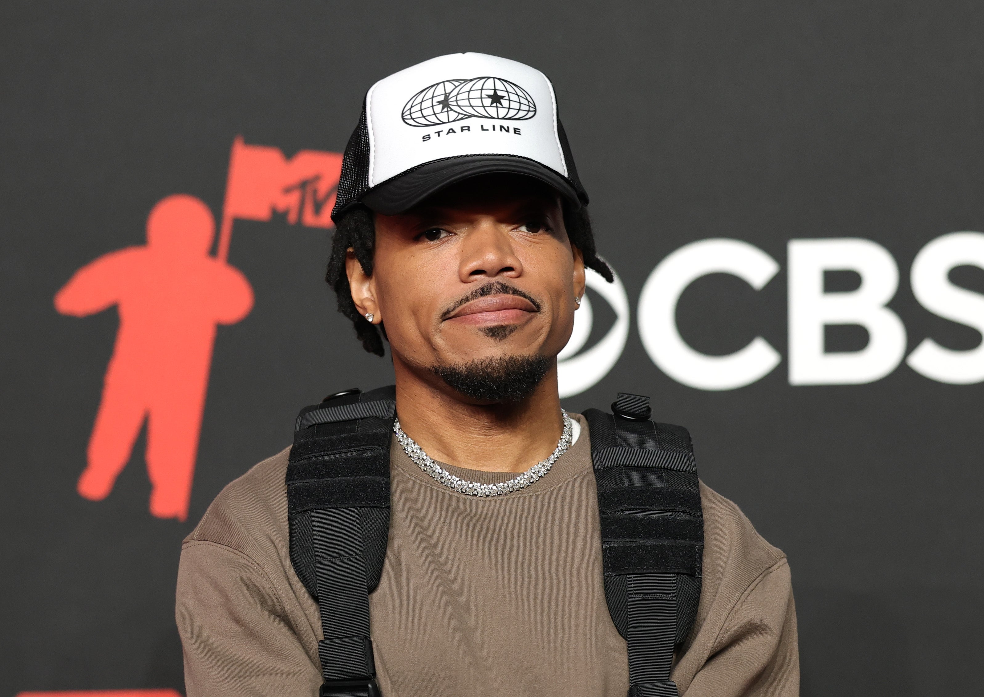 Chance the Rapper wearing a cap and casual outfit on a red carpet event