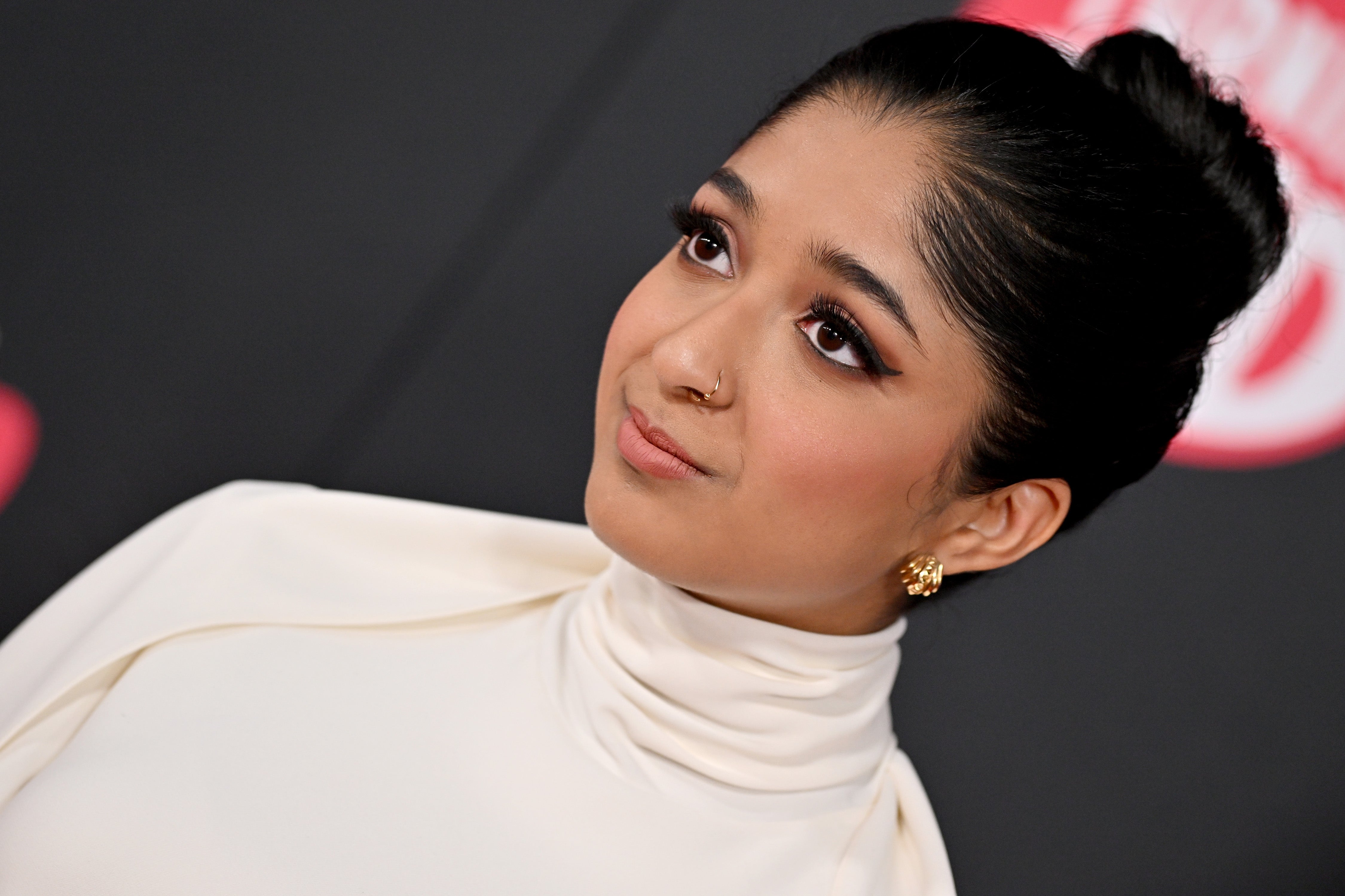 Maitreyi Ramakrishnan with elegant updo and high-neck dress gazes to the side at a possible celebrity event