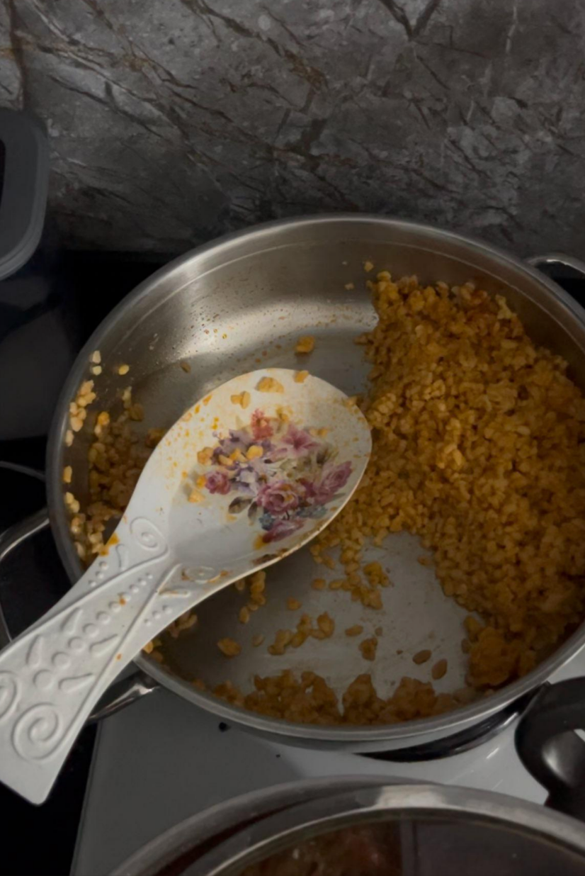 A pot with cooked lentils and a decorative spoon resting inside