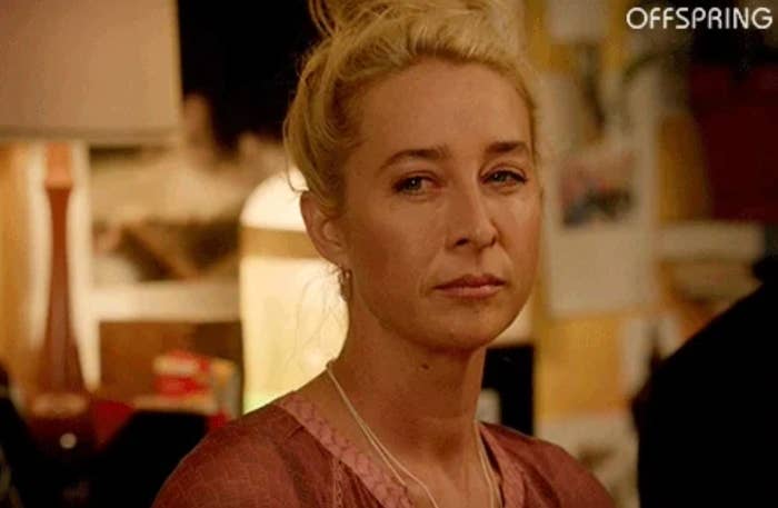 Person with a thoughtful expression, lasting  indoors. Background includes a lamp and blurred objects