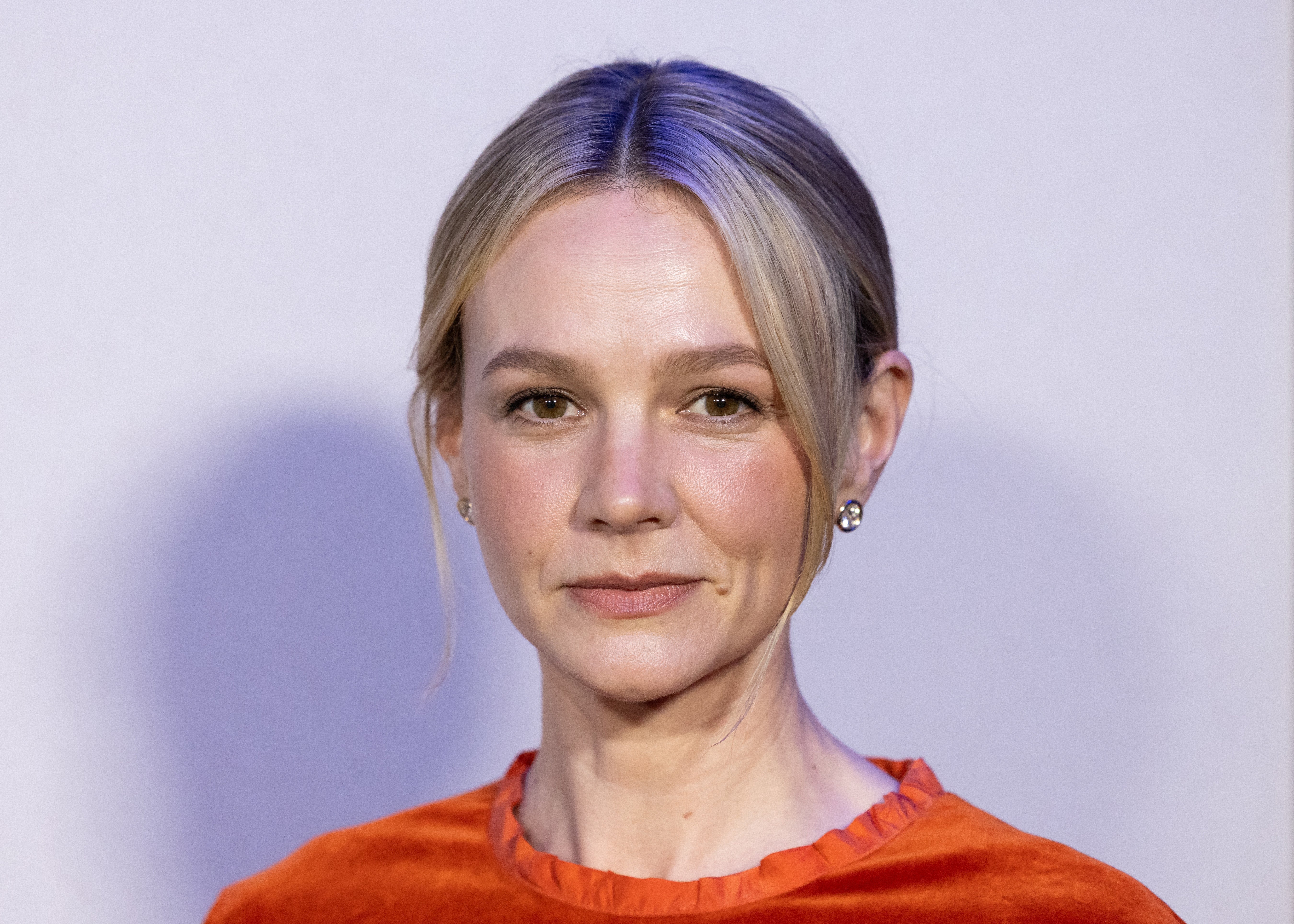Carey Mulligan in a chic outfit with a calm expression, hair tied back, and wearing simple earrings, photographed at an event