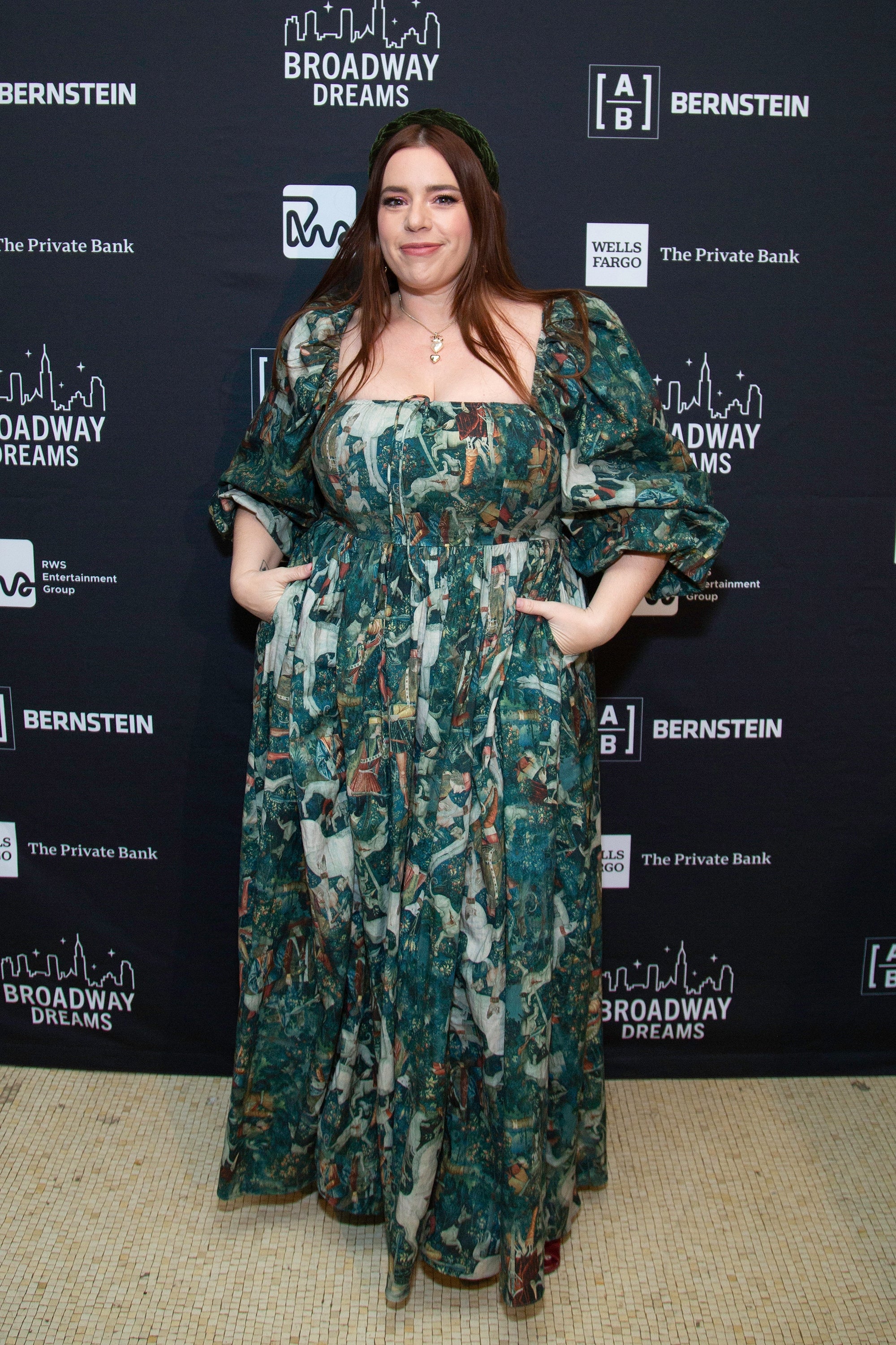 Alysha Umphress in flowy patterned dress poses at Broadway Dreams event backdrop